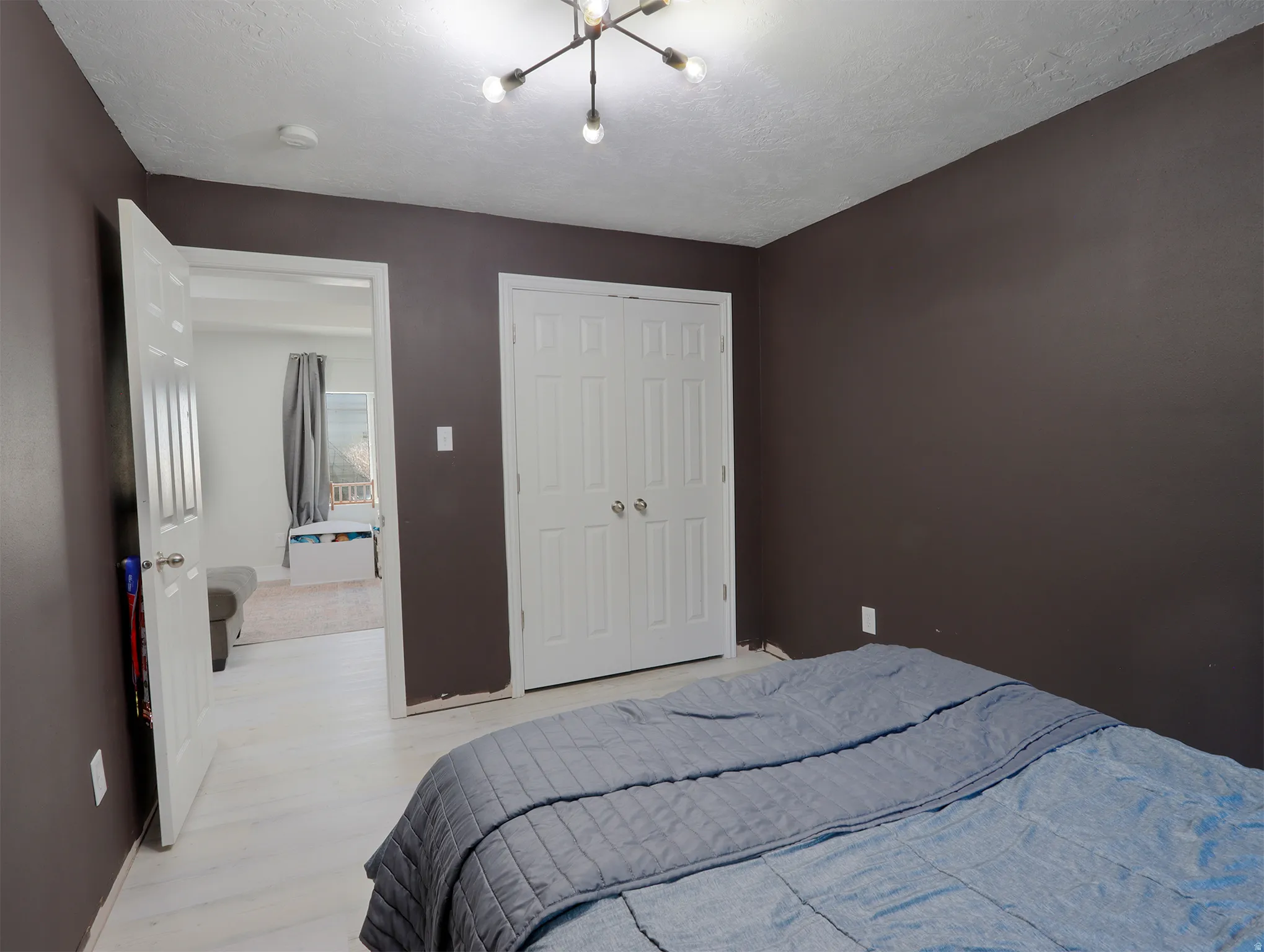 Room featuring dark accent walls, white wood-finish flooring, and a modern ceiling light fixture
