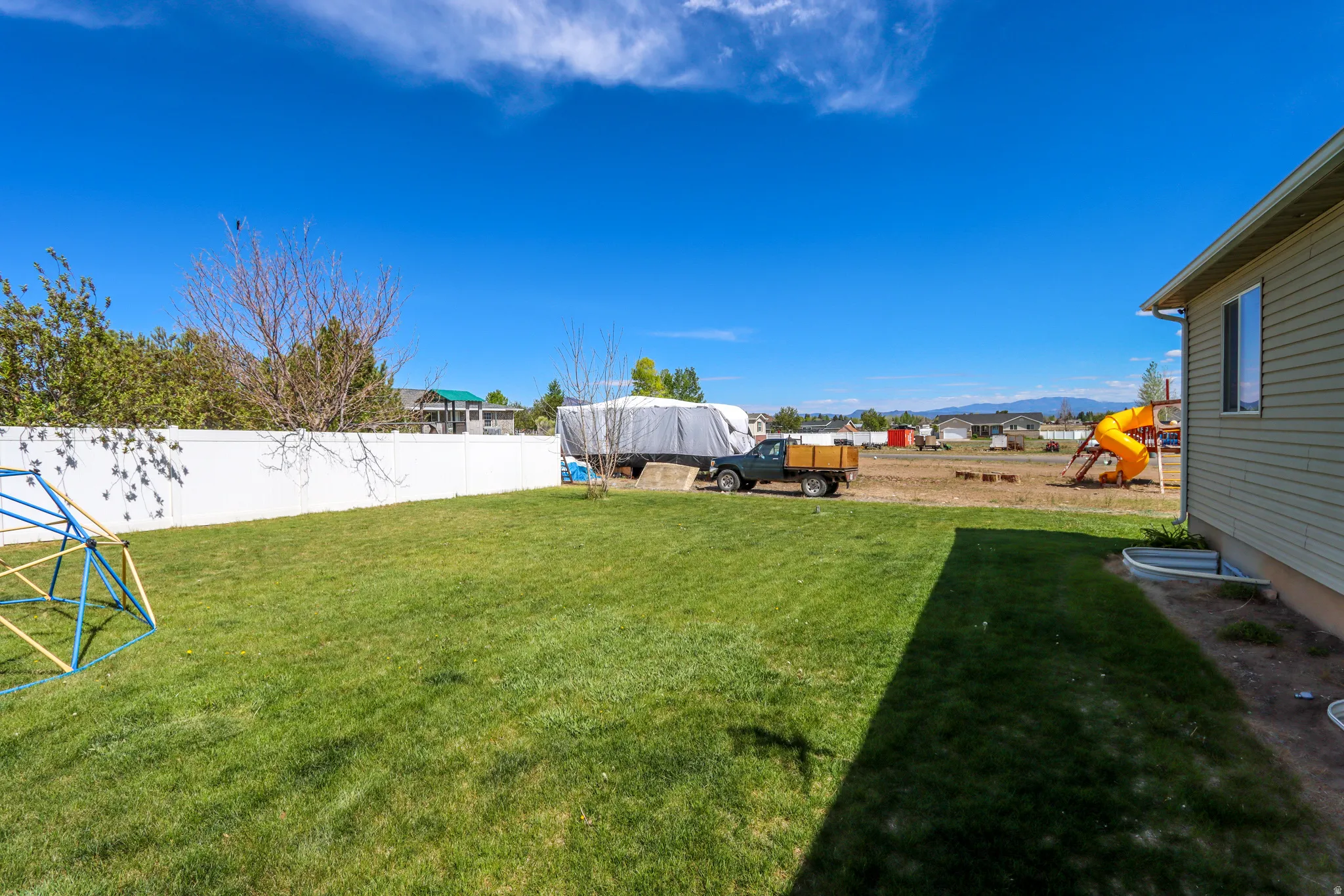 Expansive green lawn framed by a white privacy fence