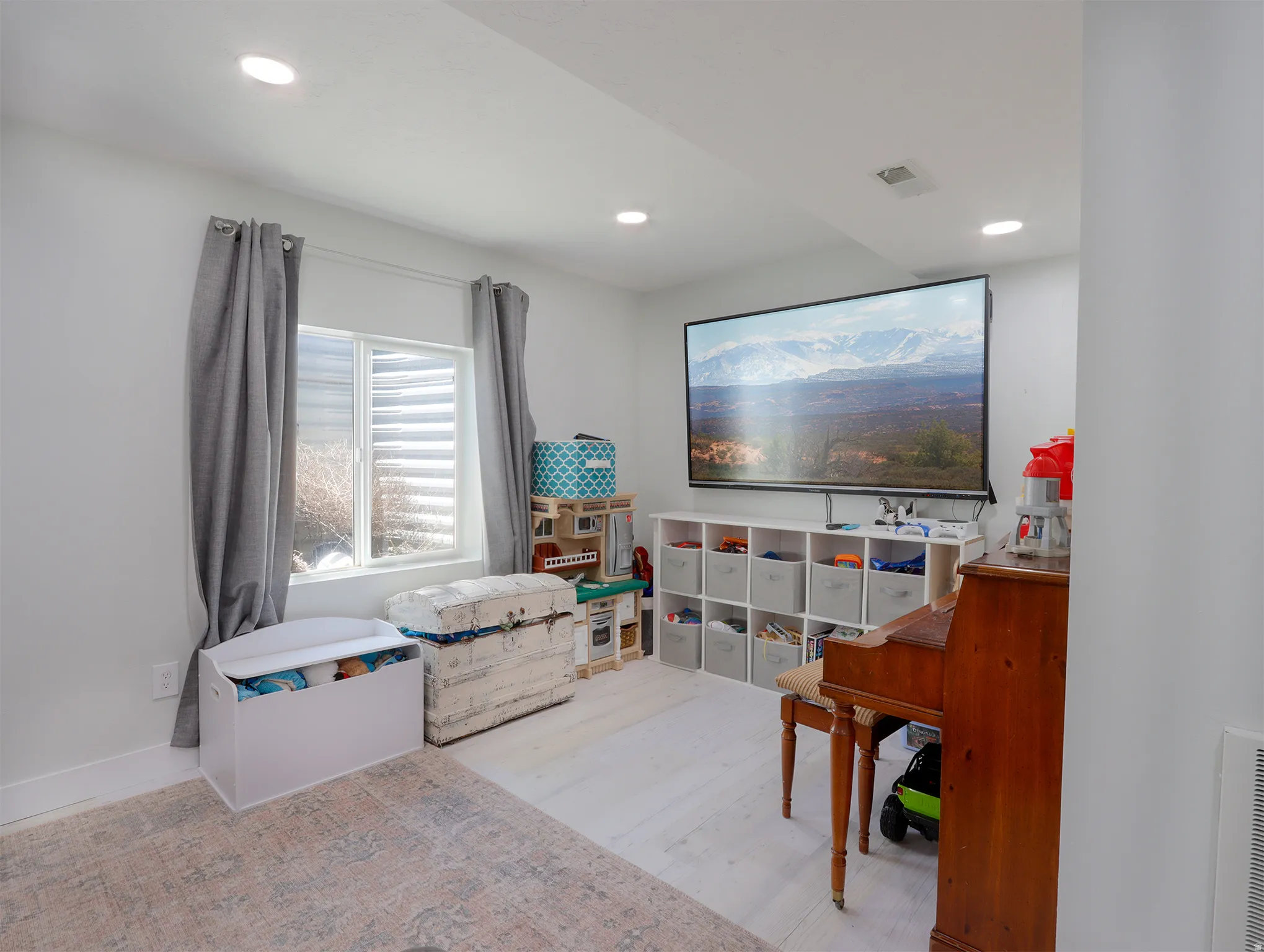 Recessed lighting illuminates this bright space featuring a large window with horizontal blinds, light wood-finish flooring, and white baseboards