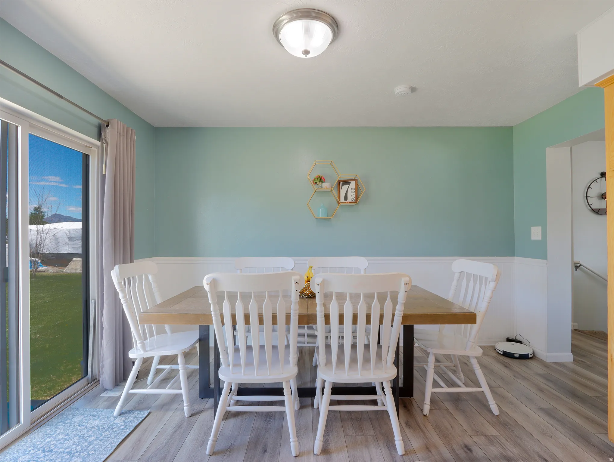 Dining area featuring wood-finish flooring, white wainscoting, and a sliding glass door providing exterior access