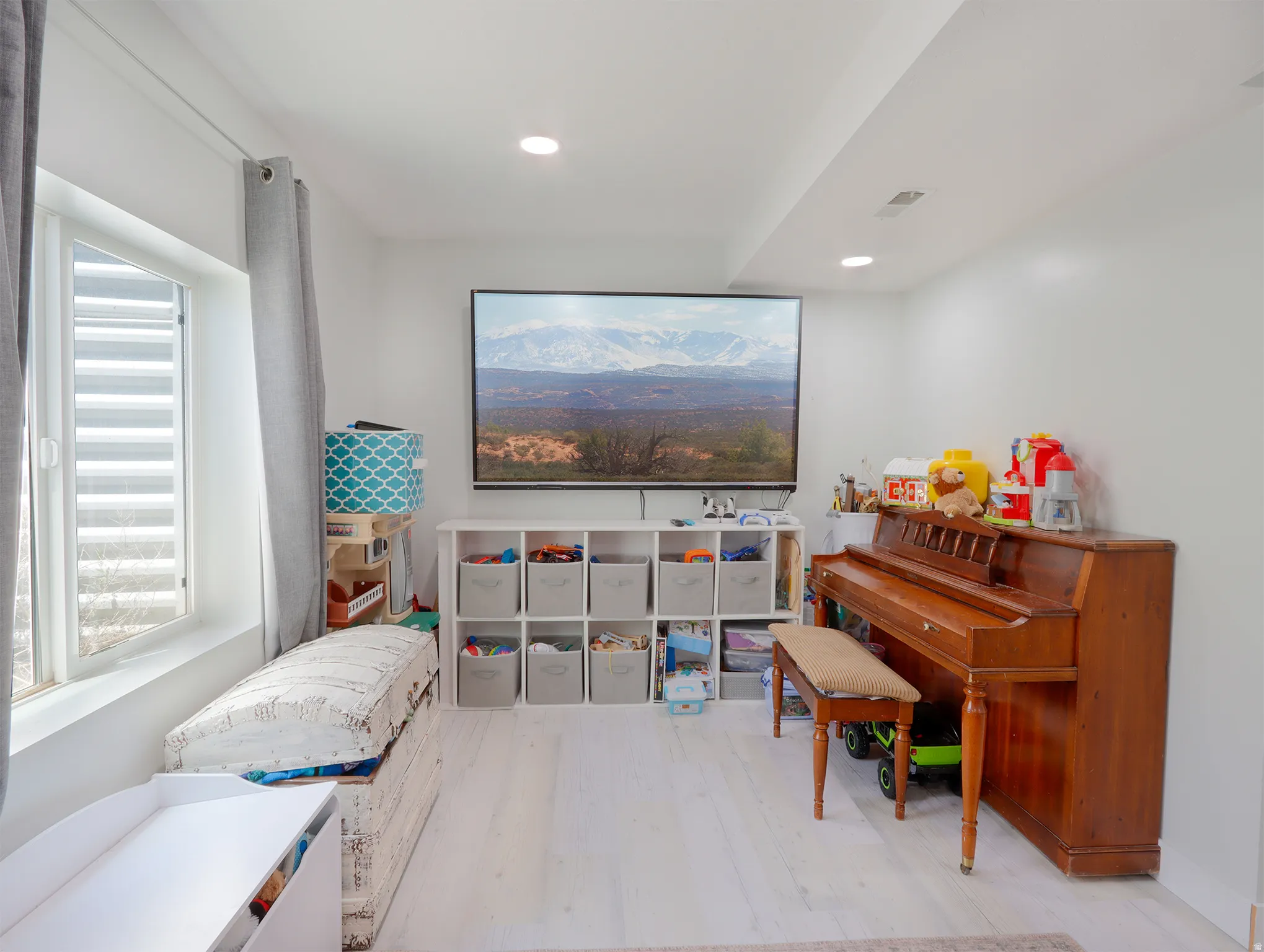 Recessed lighting illuminates the white walls and light wood-finish flooring
