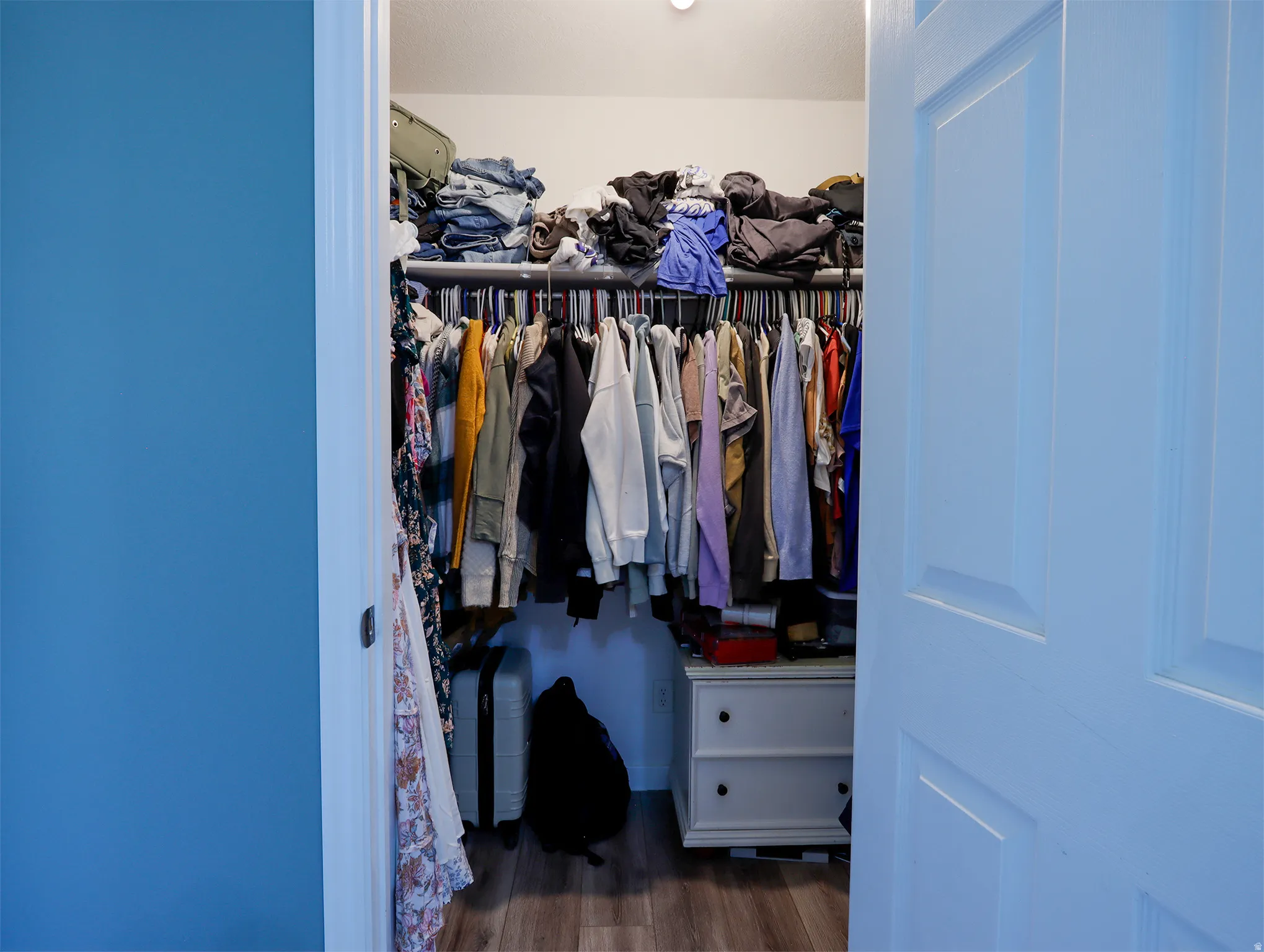 Walk-in closet featuring wood-finish flooring, recessed lighting, and white trim