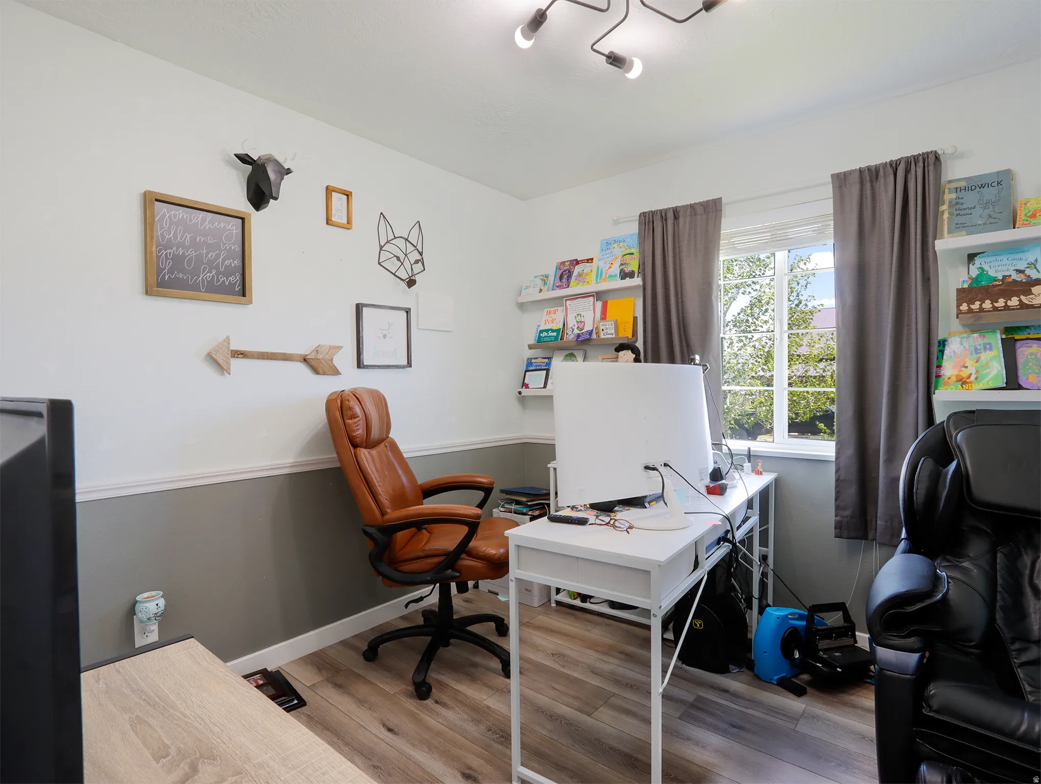 Interior room featuring wood-finish flooring, a contemporary ceiling light fixture, and a window with white framing
