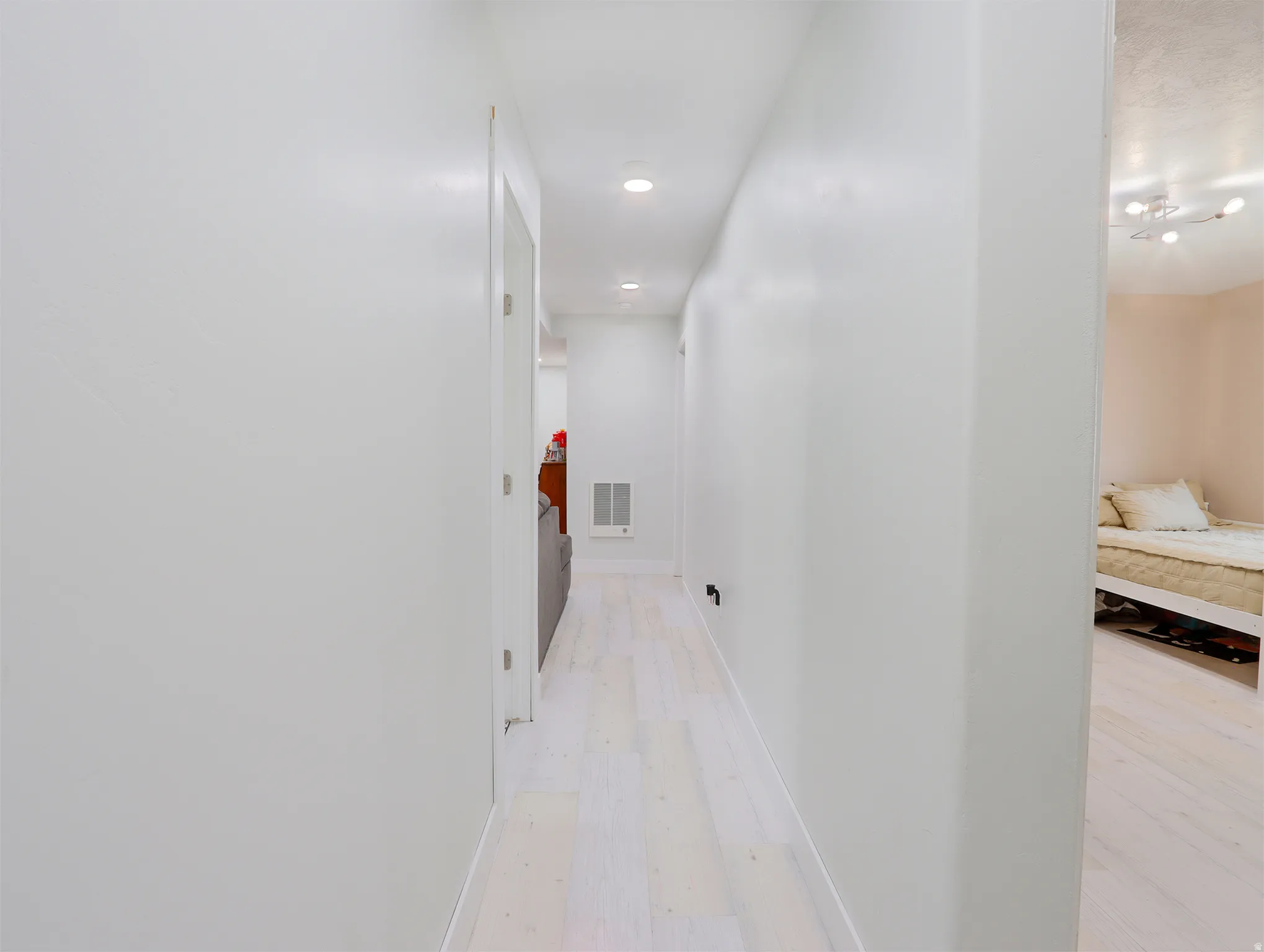 Hallway featuring light-toned wood-finish flooring, recessed lighting, and white walls