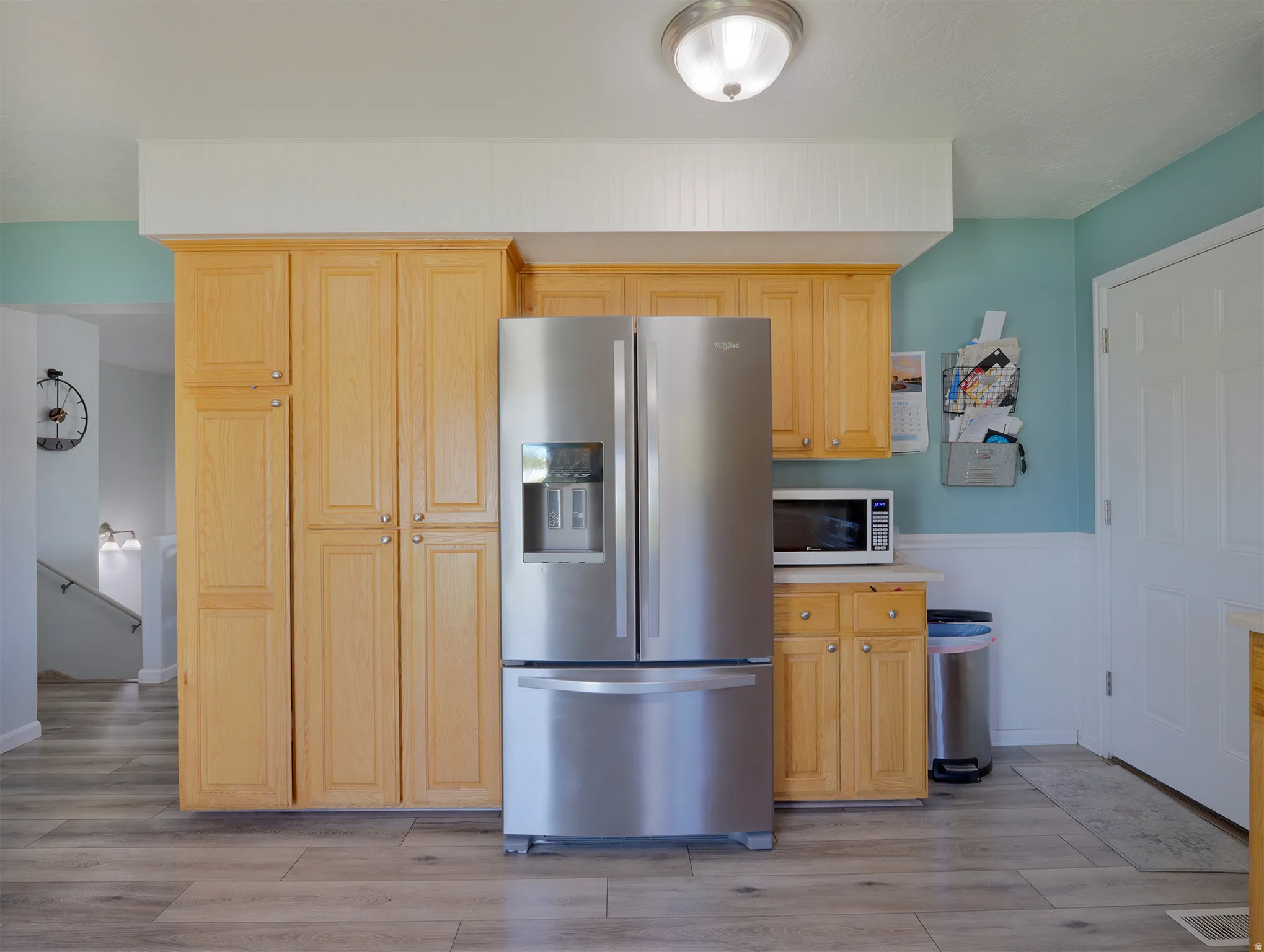 Kitchen featuring wood-finish cabinetry, stainless steel refrigerator, and wood-finish flooring