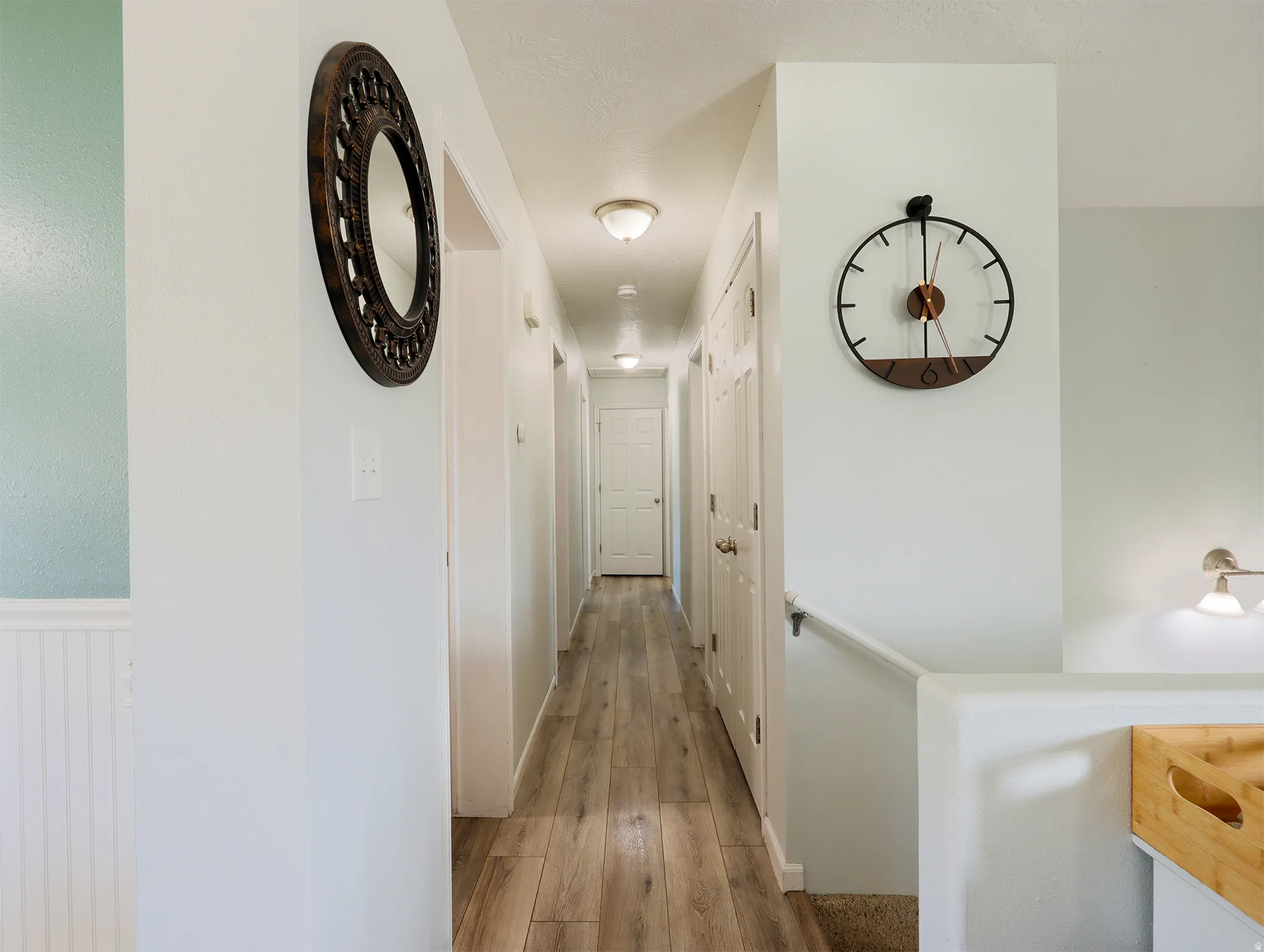Hallway featuring wood-finish flooring, white paneled doors, and ceiling-mounted flush lighting