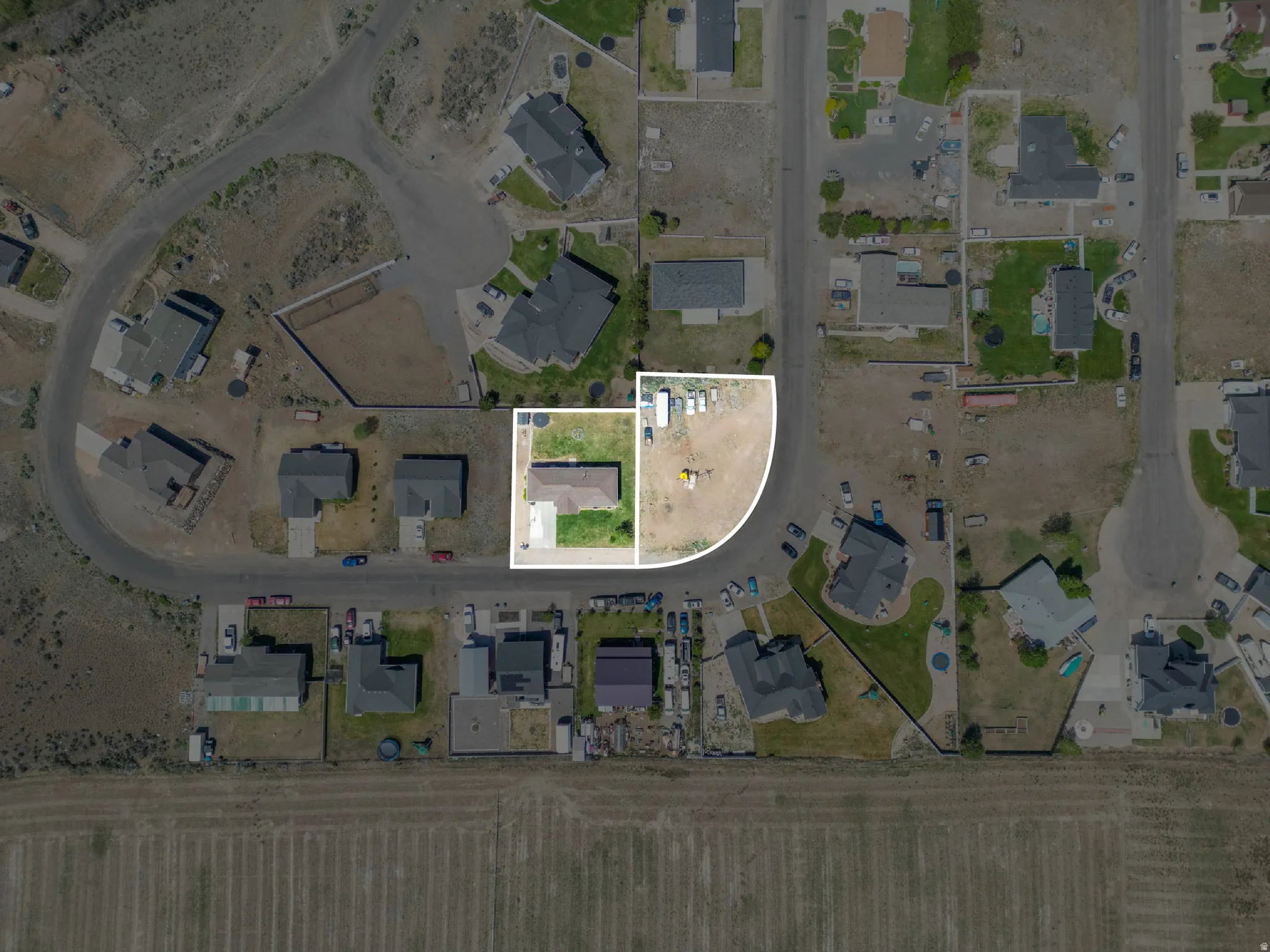 Aerial perspective showcasing a residential property with a detached home, green lawn, and gravel driveway
