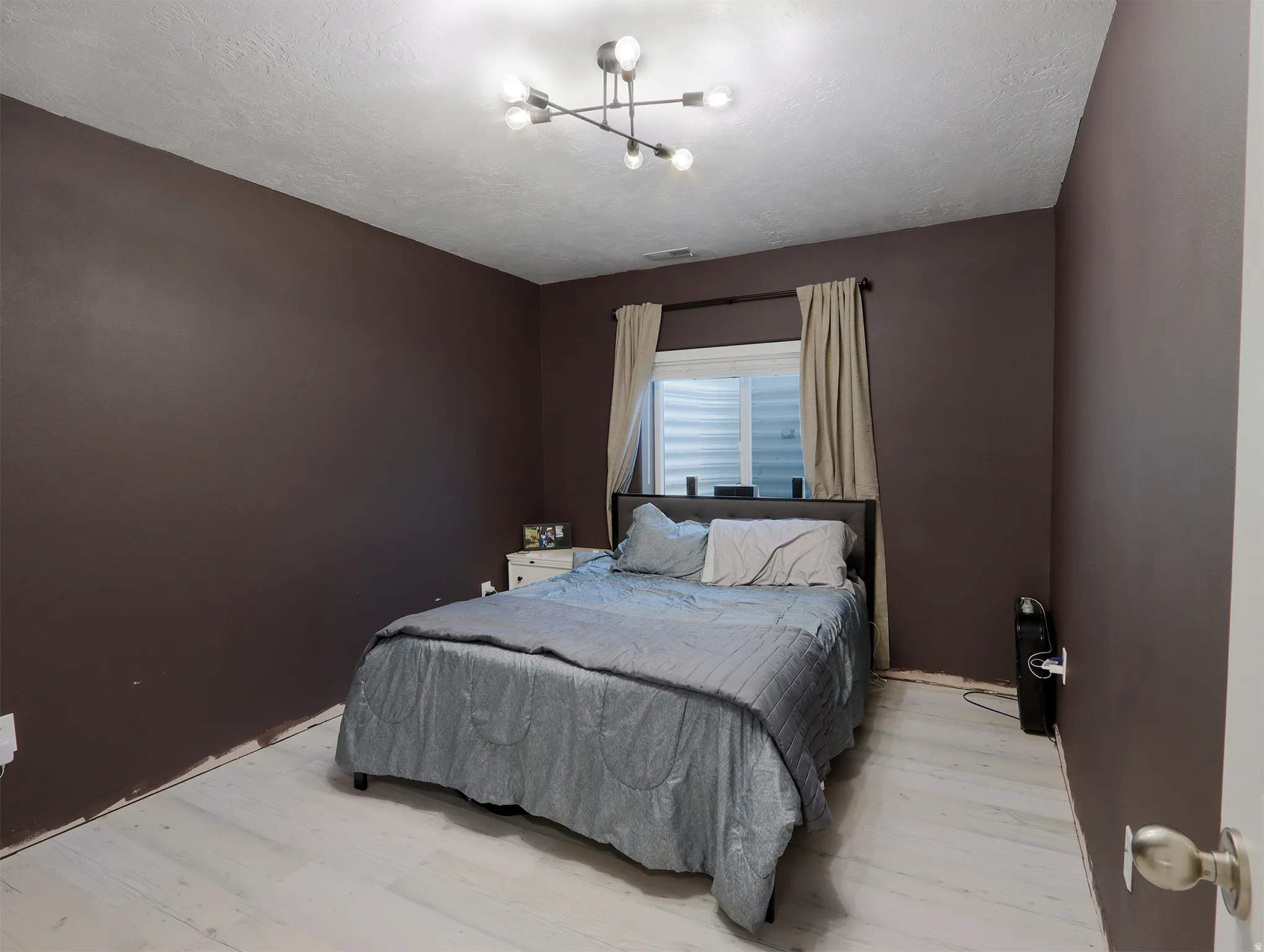 White wood-finish flooring complements dark accent walls in this bedroom
