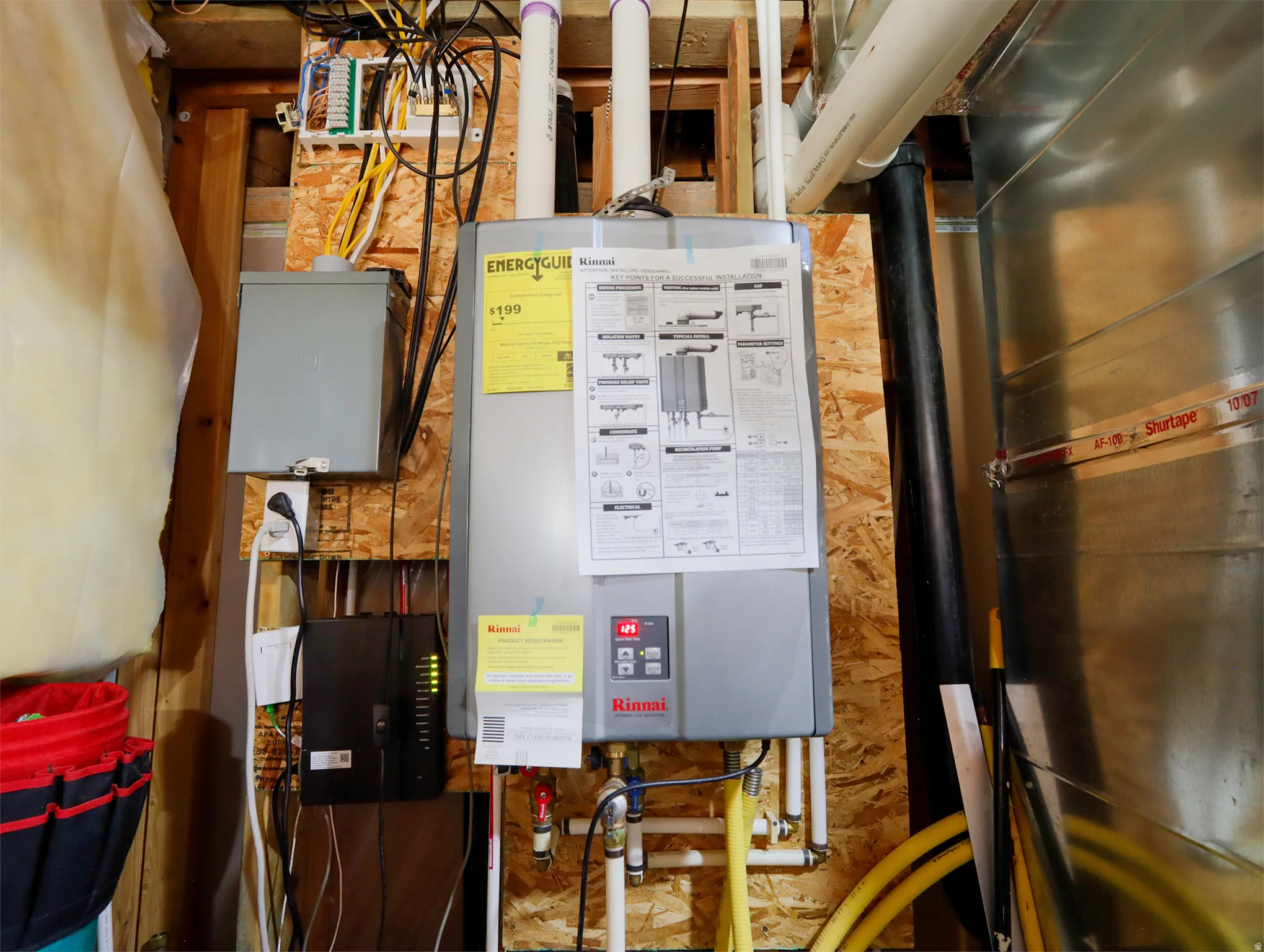Modern Rinnai tankless water heater installation, featuring a dedicated electrical box and visible utility connections