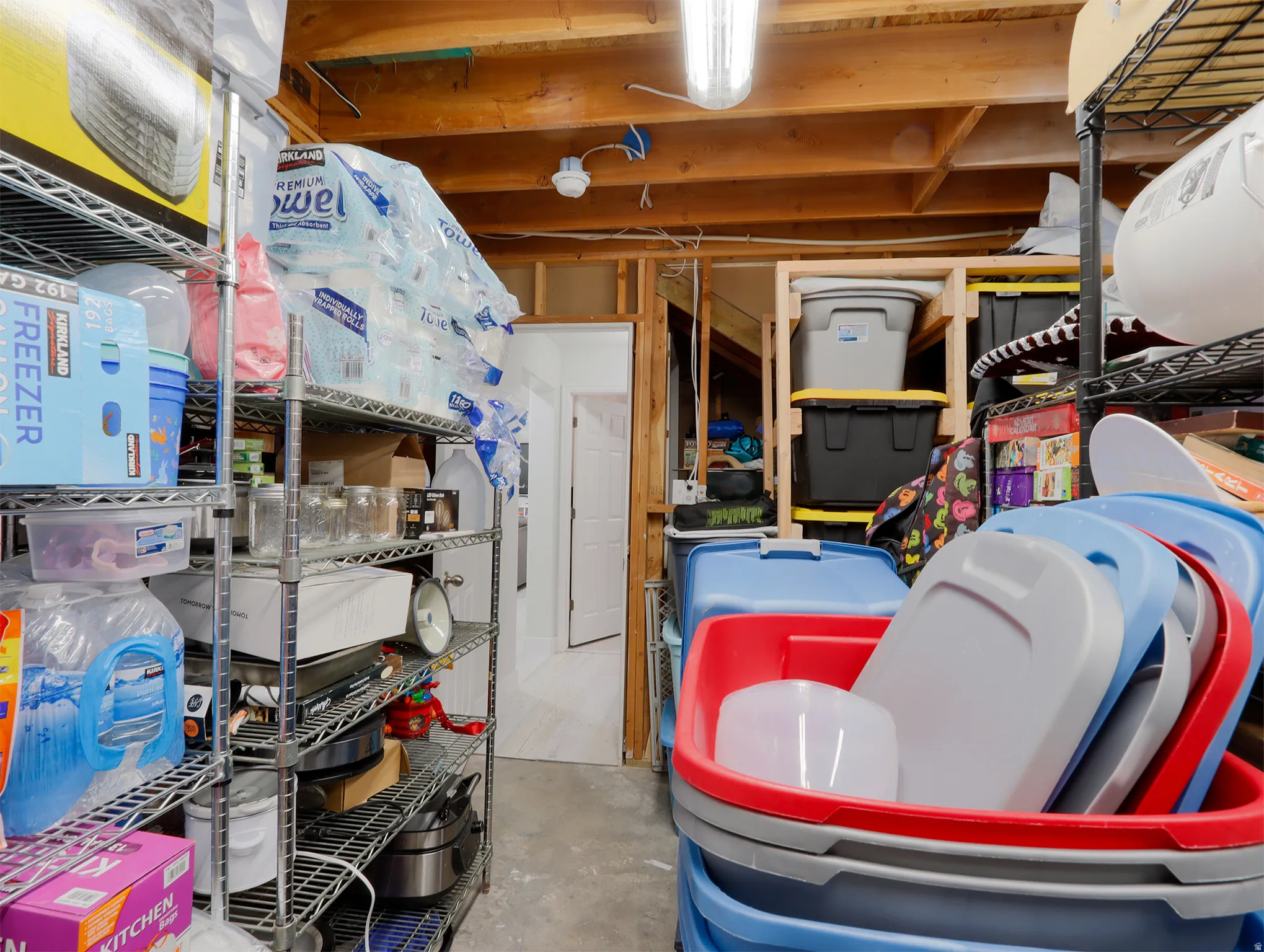 Unfinished utility space with exposed wooden ceiling joists and fluorescent lighting