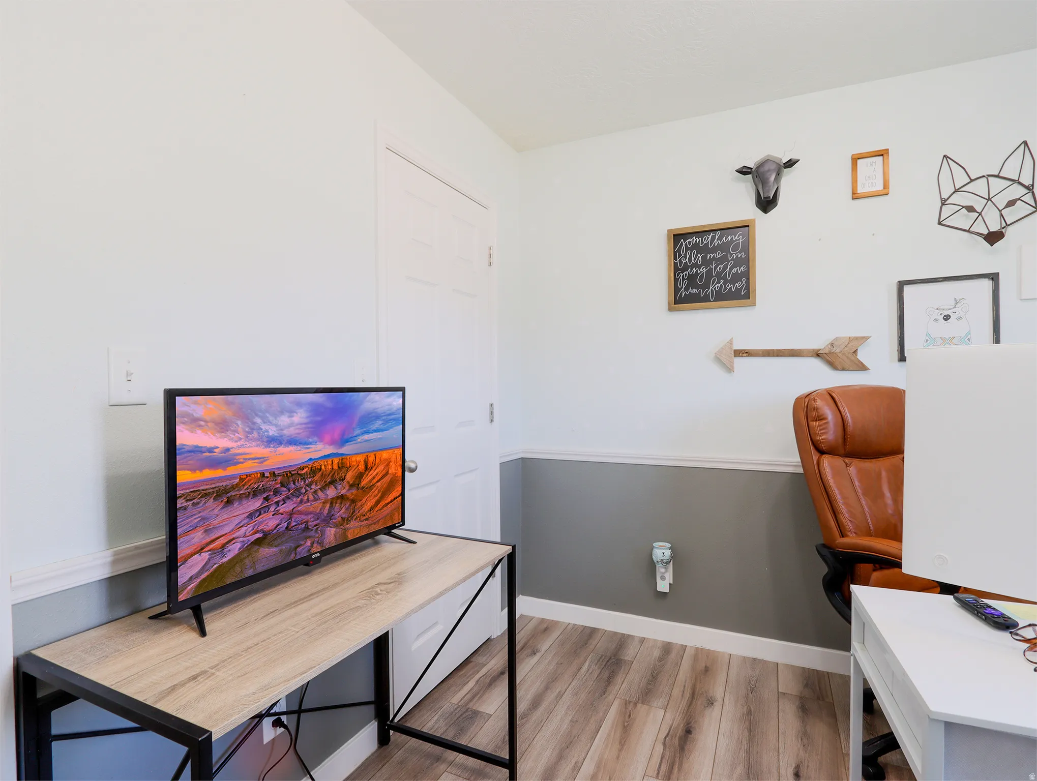 Room featuring wood-finish flooring, white baseboards, and a two-tone wall treatment with a gray lower half and a white upper half