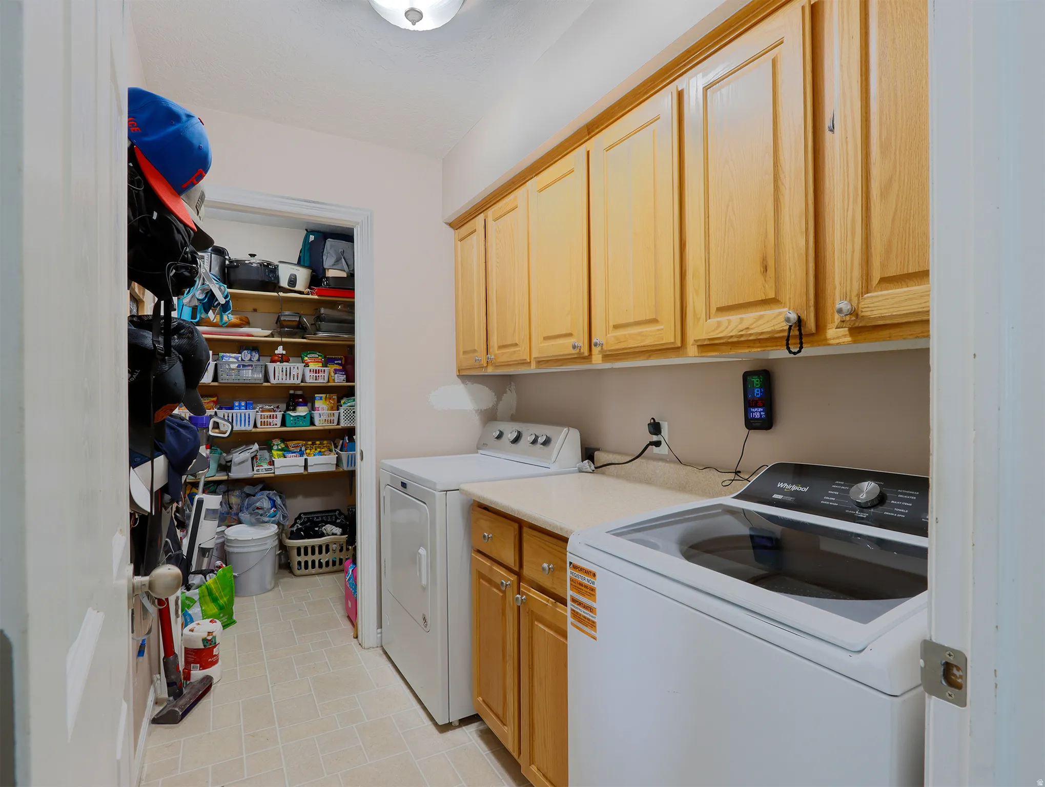 Laundry room featuring extensive upper cabinetry, a solid surface countertop, and tiled flooring