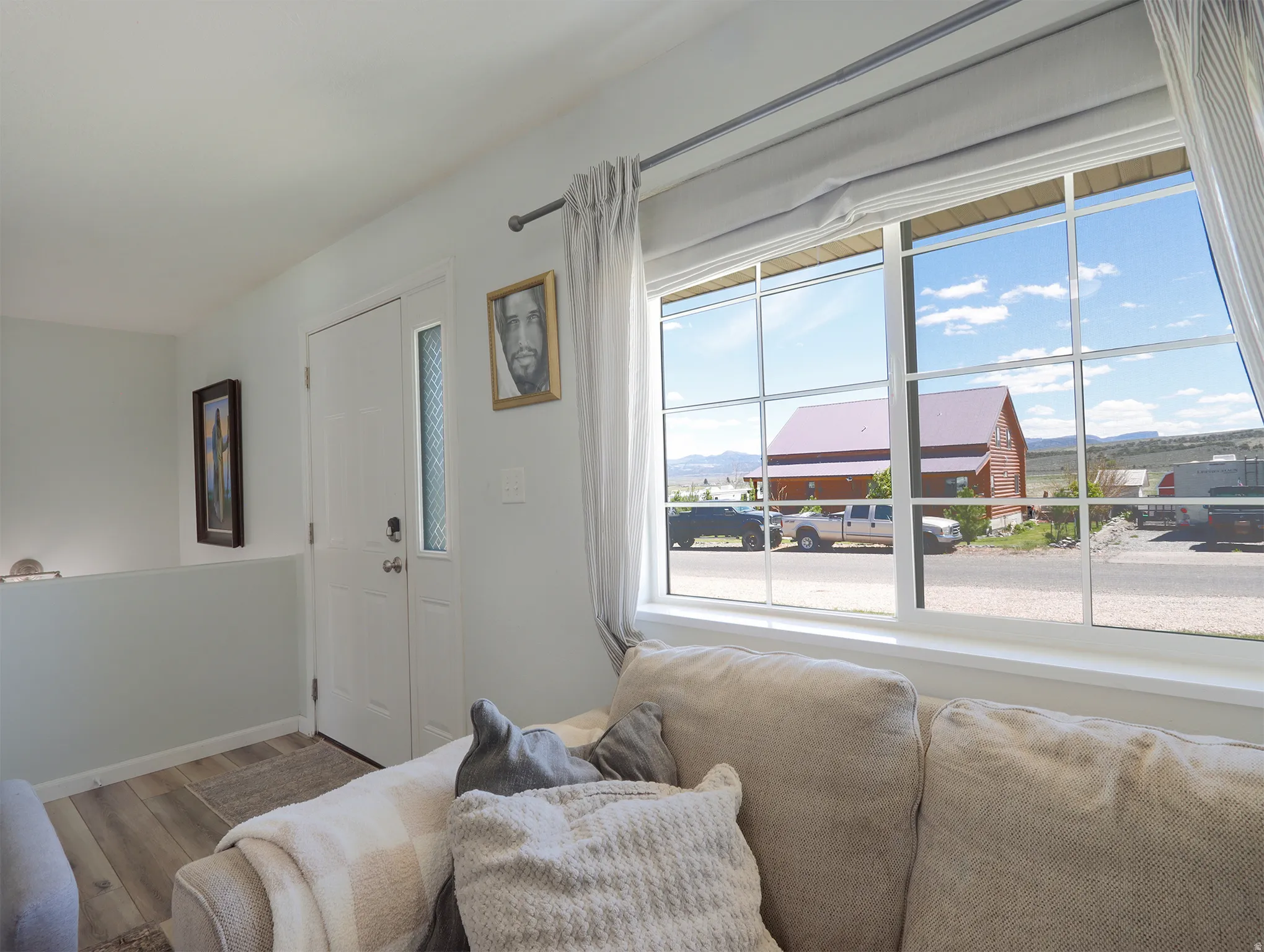 Bright interior with white walls, wood-finish flooring, and an entry door featuring a vertical glass insert
