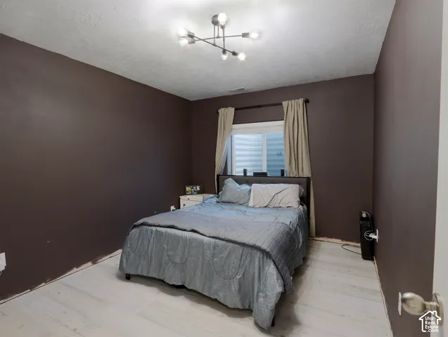White wood-finish flooring complements dark accent walls in this bedroom