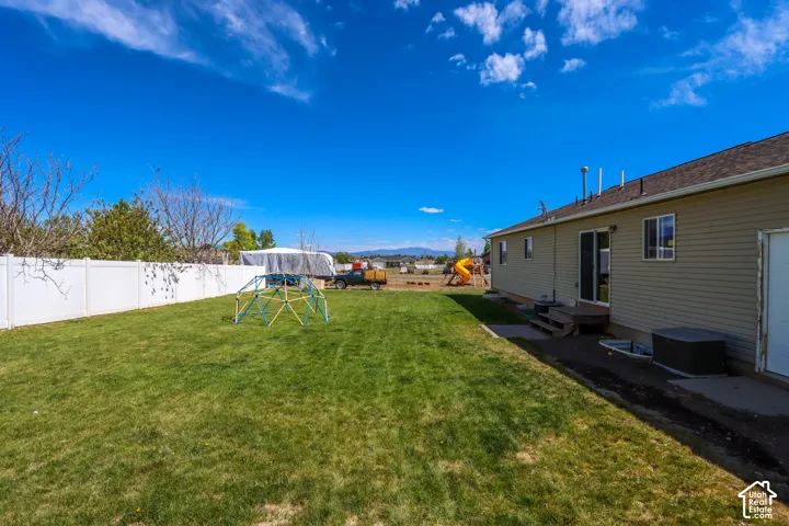 Spacious backyard featuring a manicured lawn, white privacy fencing, and a neutral-toned residential exterior