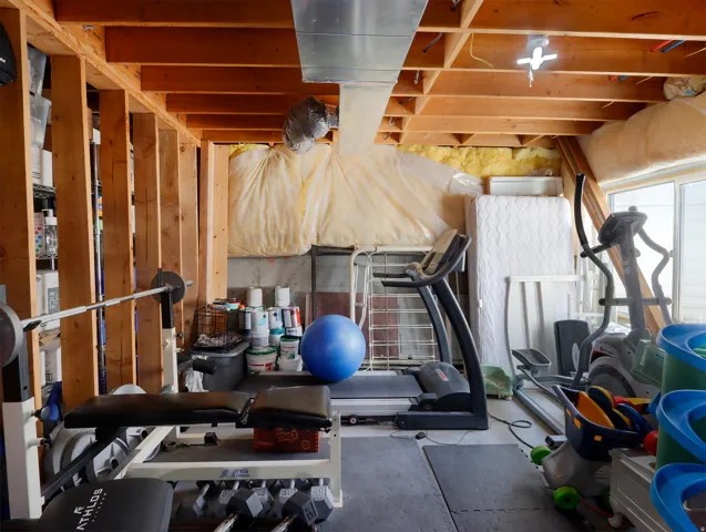 Unfinished basement space featuring exposed wood joists and structural beams, concrete foundation walls, and visible ductwork