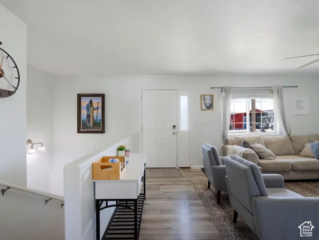 Entryway featuring wood-finish flooring, a white front door with decorative glass sidelight, and a built-in wall sconce