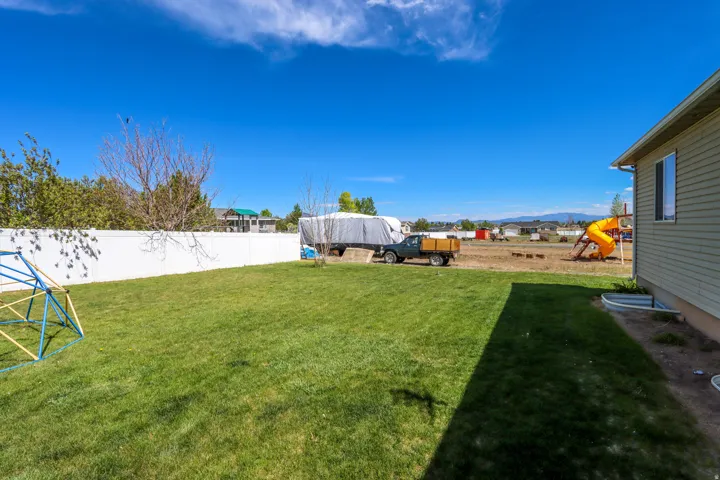 Expansive green lawn framed by a white privacy fence