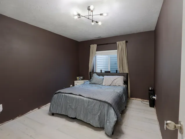White wood-finish flooring complements dark accent walls in this bedroom