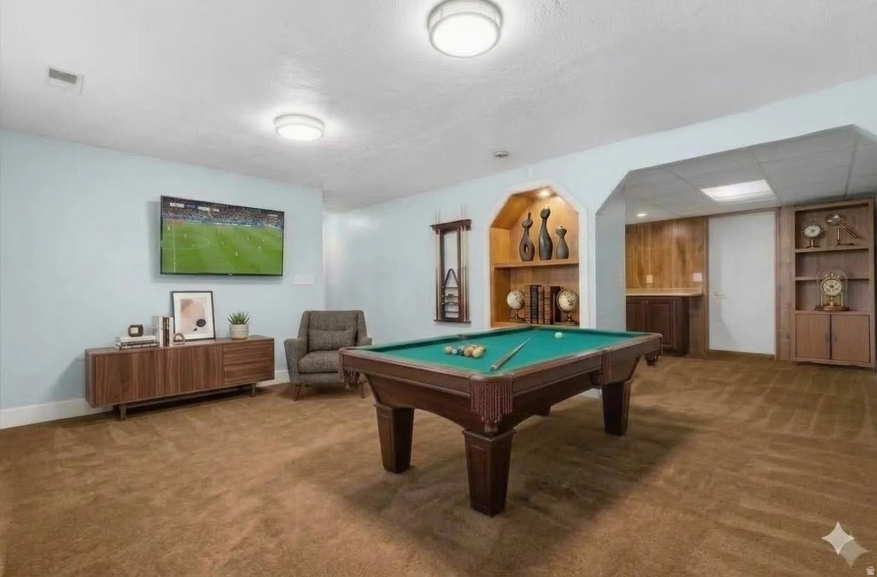 Spacious recreation room featuring recessed built-in shelving, a built-in wet bar with wood-finish cabinetry, light blue wall paint, and brown carpet flooring
