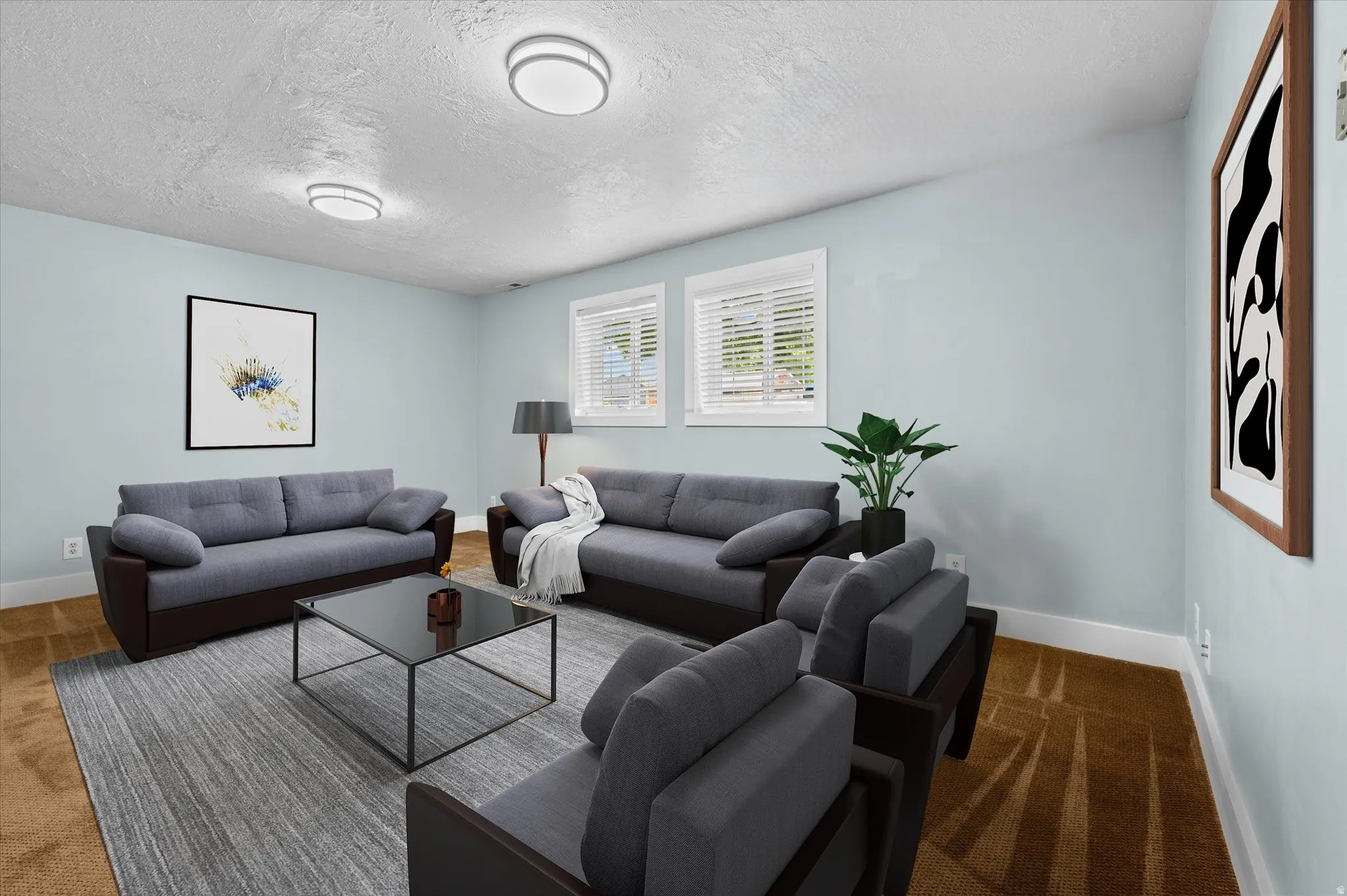 Spacious living area featuring light blue walls, two windows with white blinds, and ceiling-mounted light fixtures