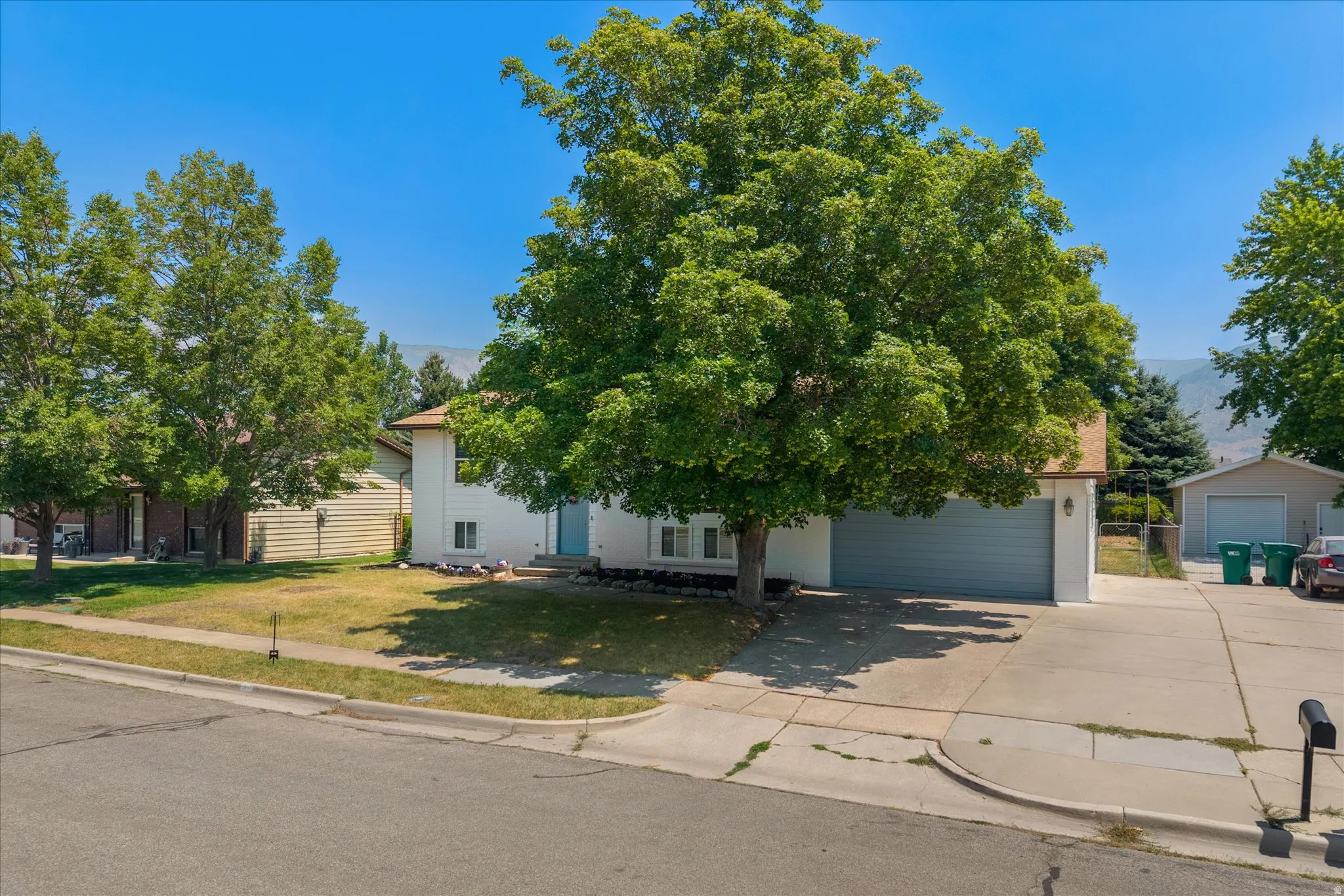 Two-story residence featuring a two-car garage, established front yard tree, and an additional detached garage with an extended driveway