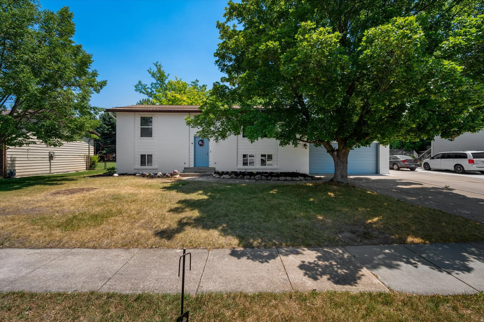 Split-level residence featuring a white exterior with a light blue front door, an attached two-car garage with light blue doors, and a concrete driveway