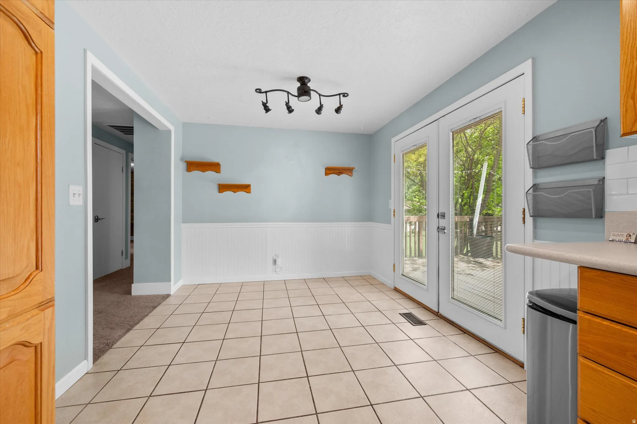 Kitchen semi formal Dining area with Tile flooring throughout, featuring a white wainscoting accent wall and light blue wall paint