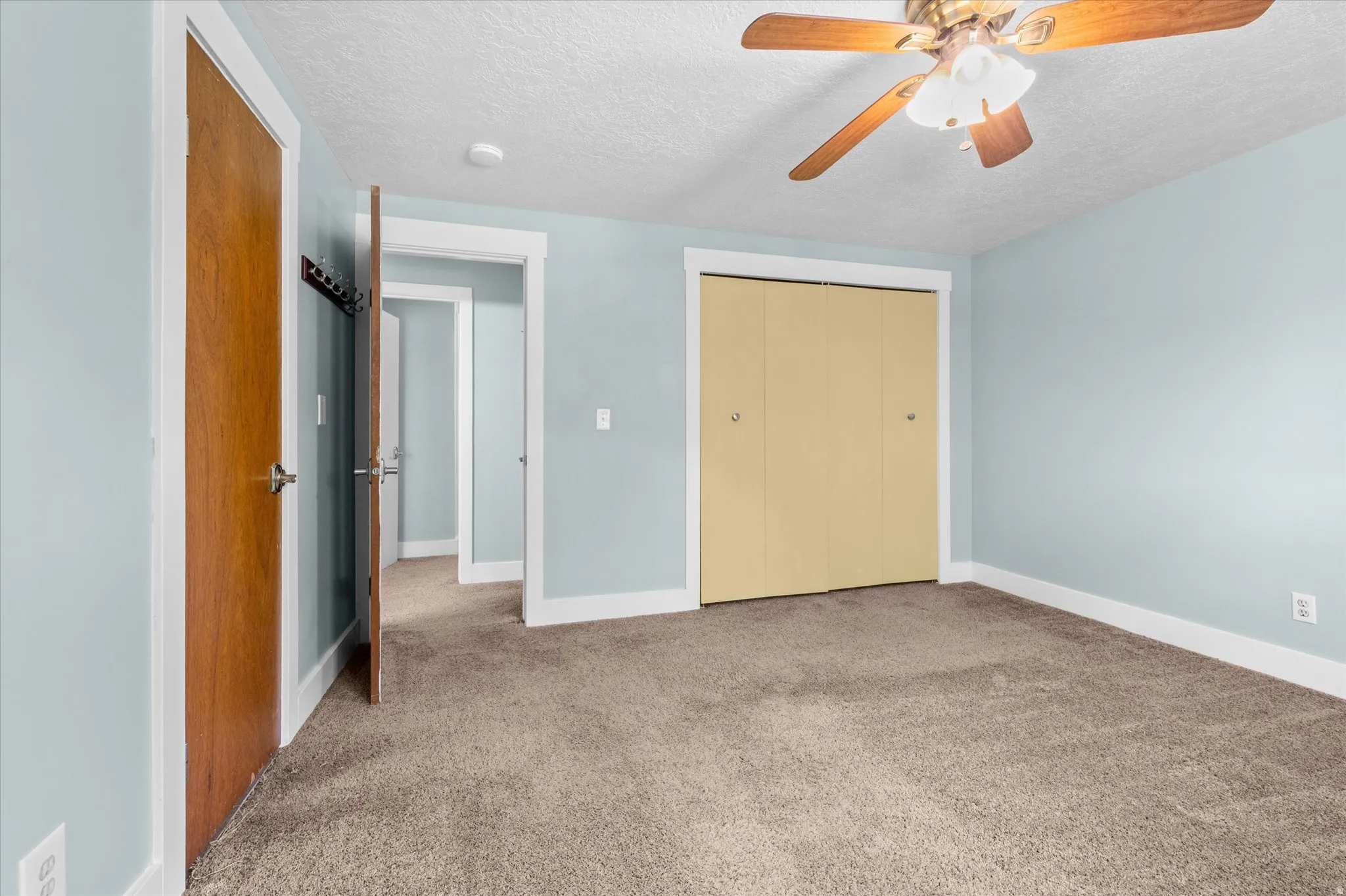 Carpeted Primary bedroom featuring a closet with bi-fold doors and an entrance to a bathroom