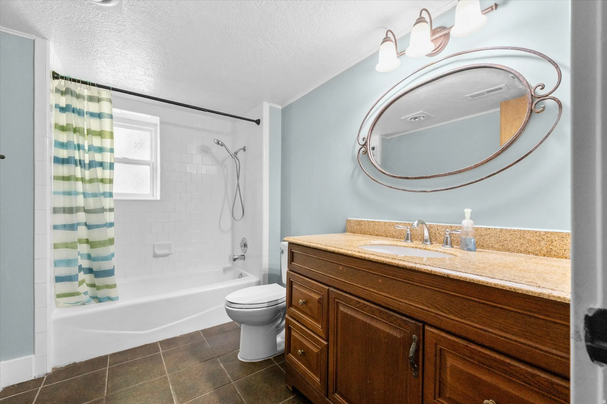Bathroom featuring a white subway tile shower, a window within the shower, and dark floor tiles