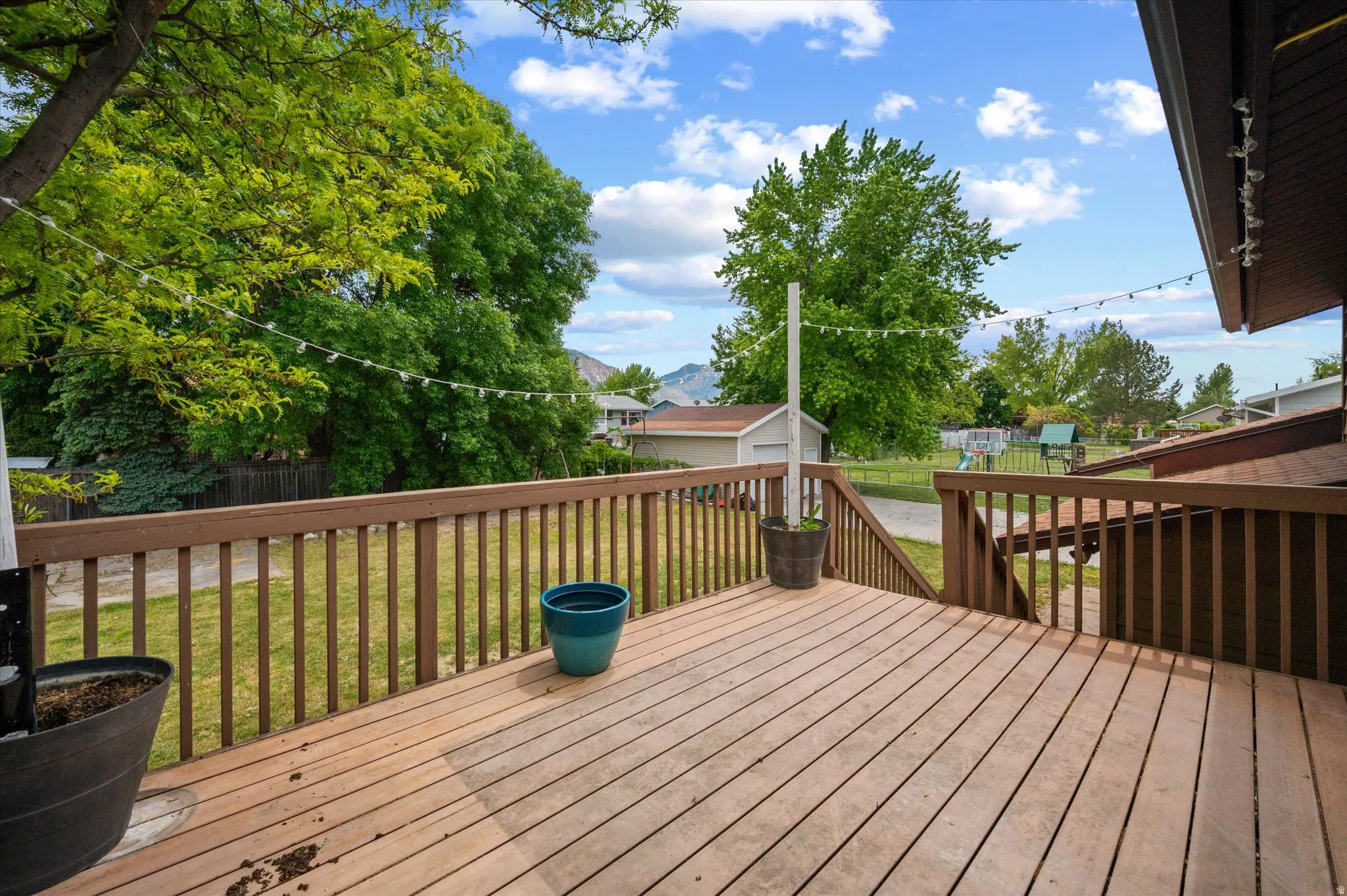 Wood deck with a railing, outdoor lighting,  and steps down to the yard