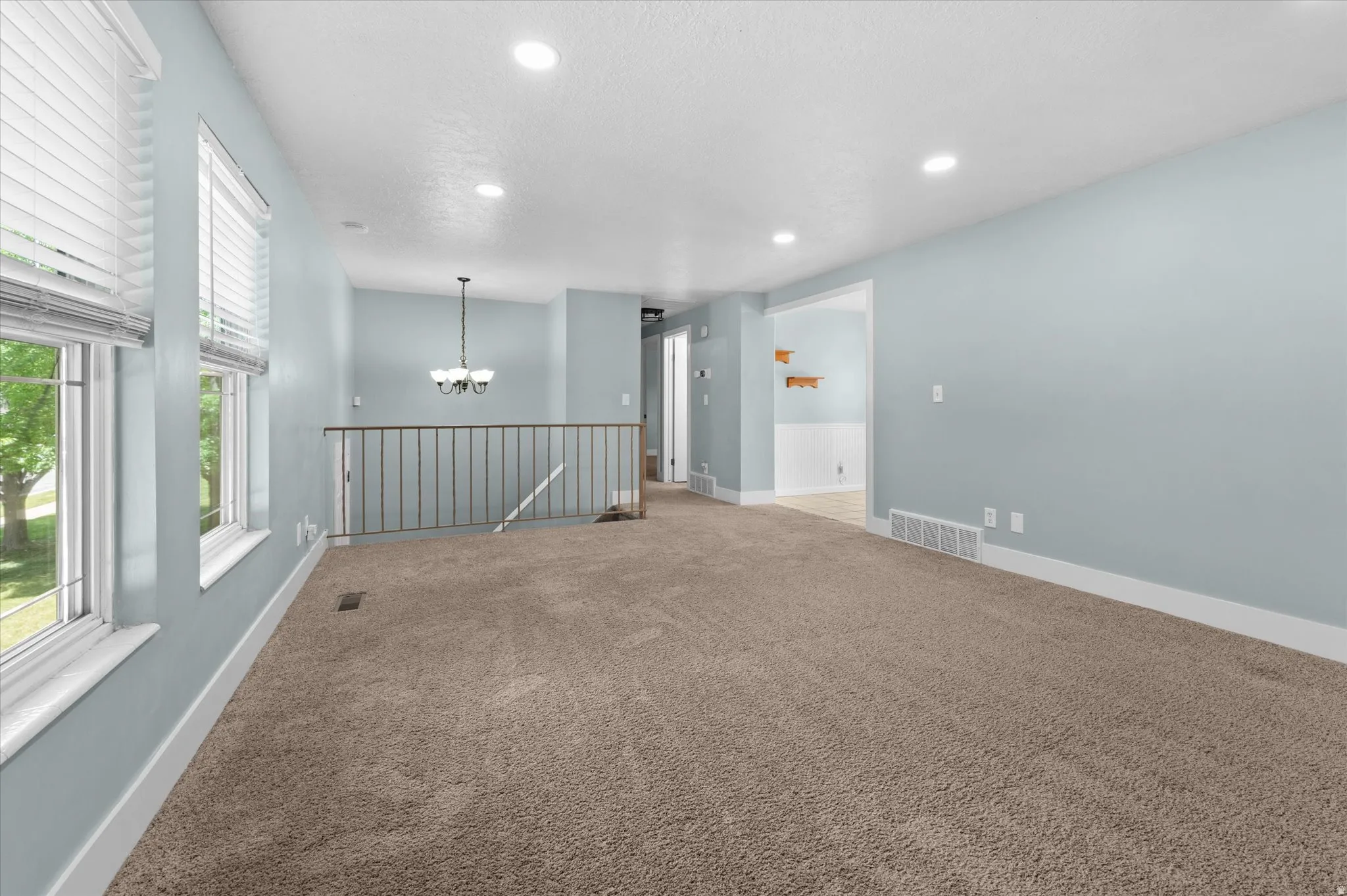 Open-concept living area featuring light blue walls and neutral carpet