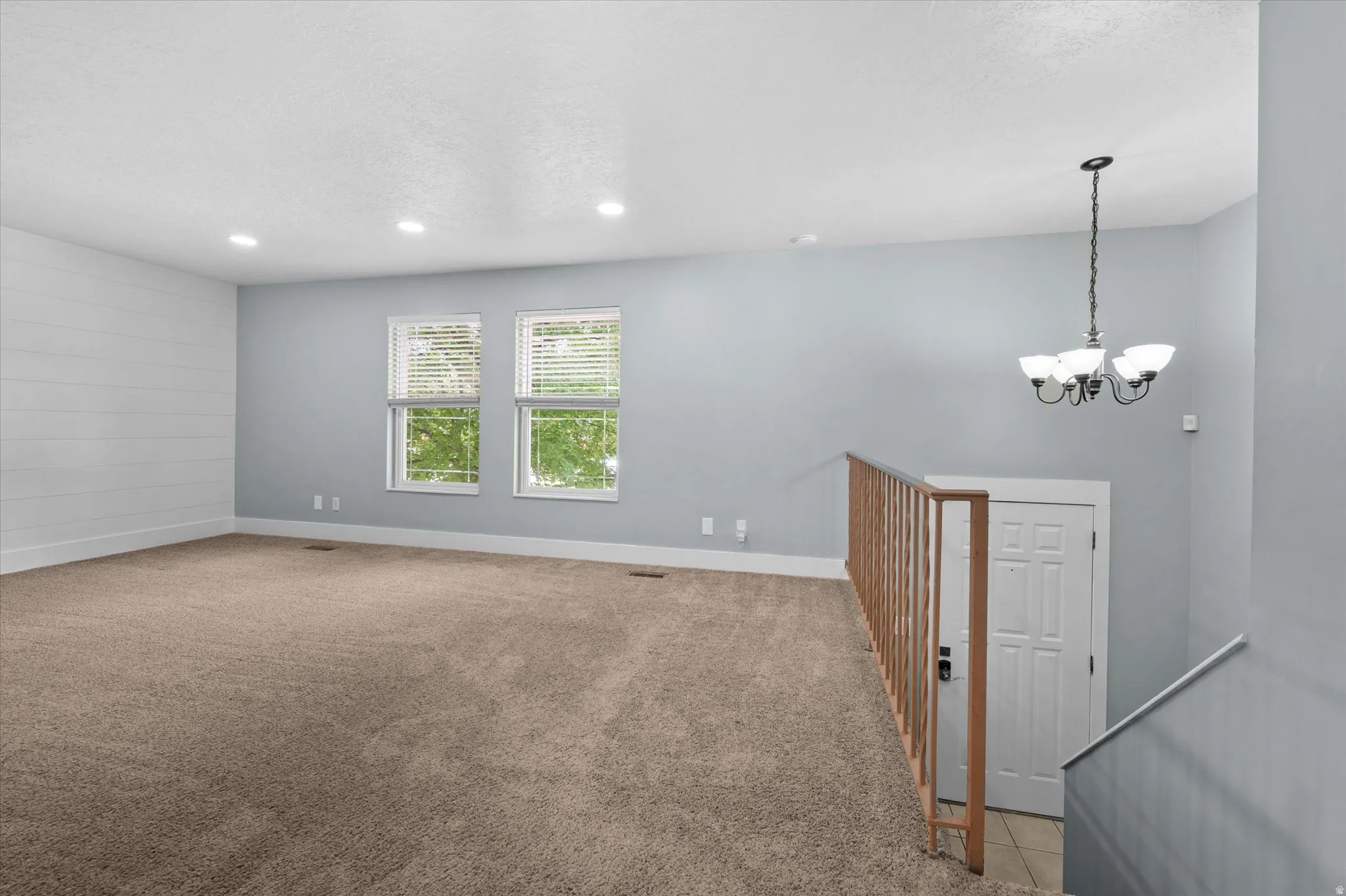 Upper-level living area with neutral carpeting and a shiplap accent wall