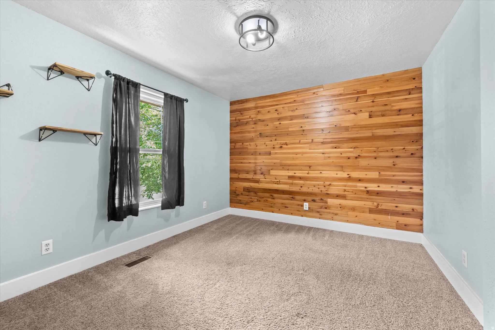 Bedroom #2 featuring a striking wood-panel accent wall, neutral carpeting, and a modern ceiling light fixture