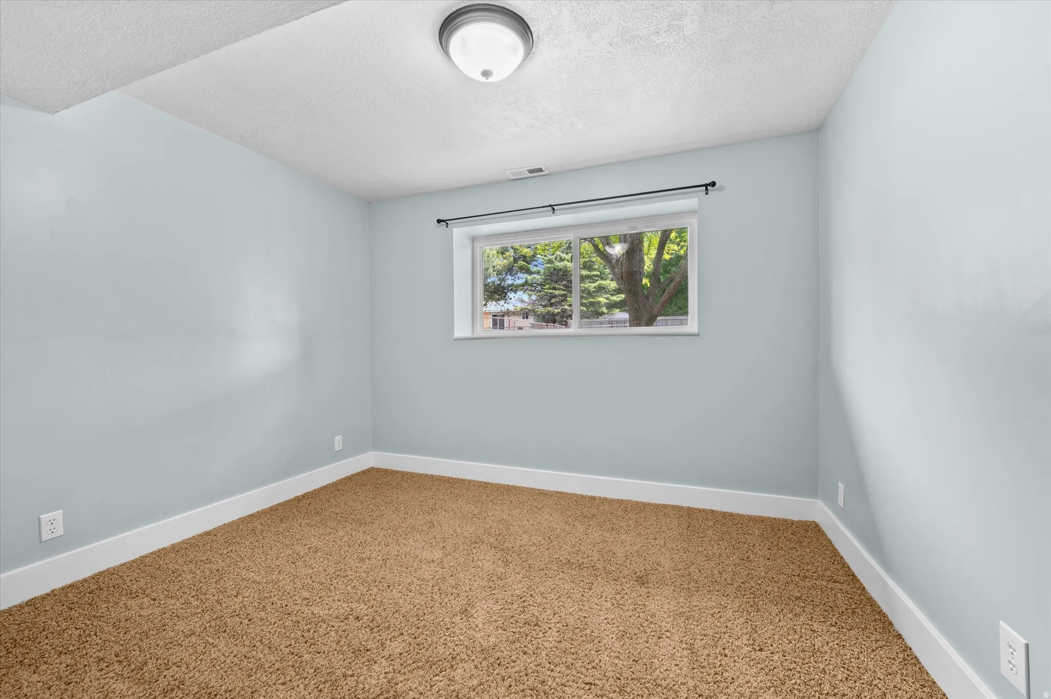 Bedroom #3 featuring light blue walls, brown carpet, white baseboards, and a window with natural light
