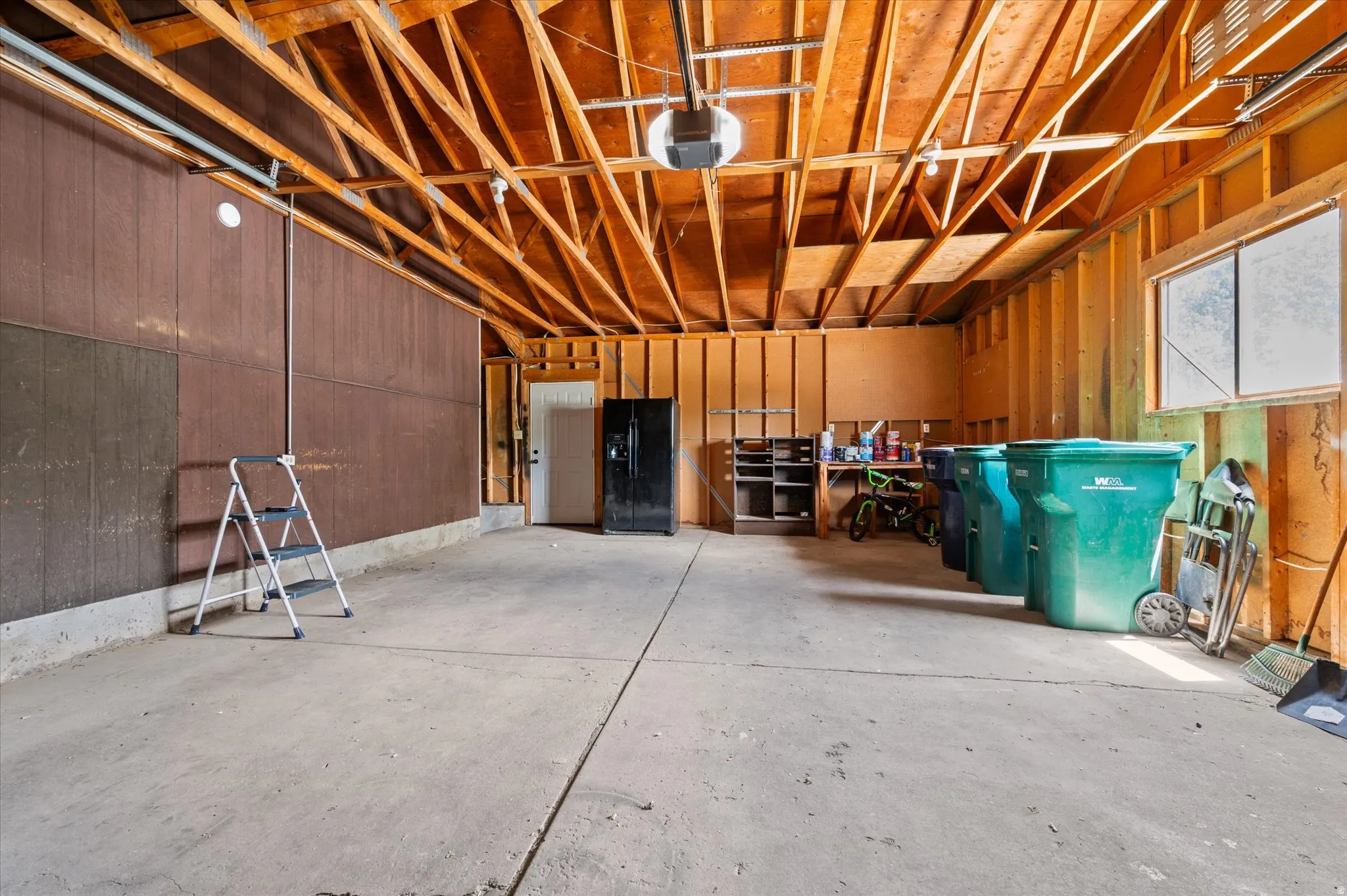 Spacious garage, a large window providing ambient light, entrance to backyard and basement