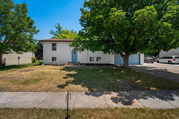 Split-level residence featuring a white exterior with a light blue front door, an attached two-car garage with light blue doors, and a concrete driveway