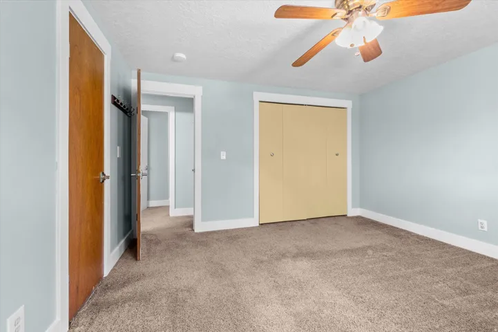 Carpeted Primary bedroom featuring a closet with bi-fold doors and an entrance to a bathroom