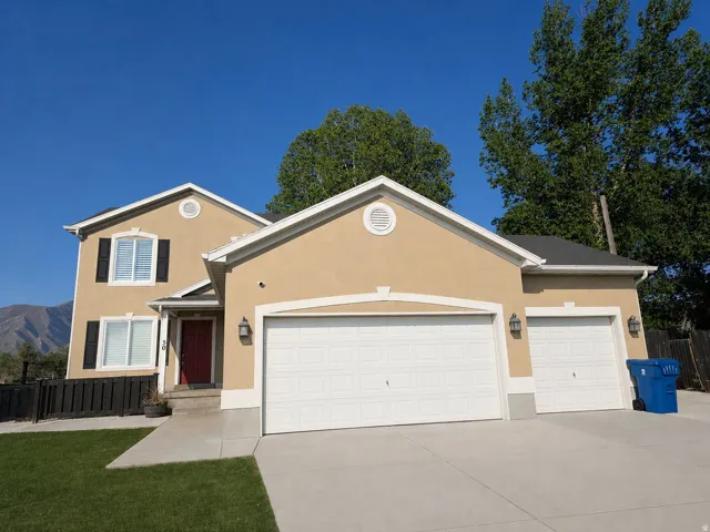 Stucco exterior featuring a two-car garage, red entry door, and black shutters