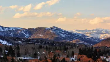 Expansive mountain scenery featuring snow-dusted peaks, evergreen forests, and varied tree coverage