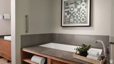 Built-in soaking tub with a stone-finish surround, contemporary faucet, and adjacent built-in shelving