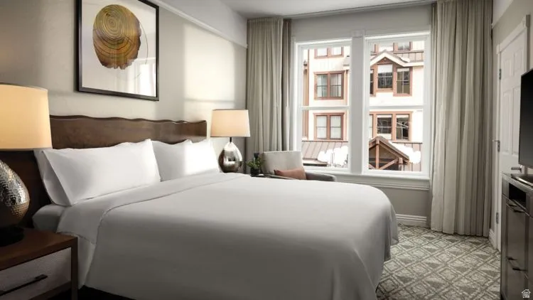 Bedroom featuring a wood-finish headboard, patterned carpet, and large windows with architectural details