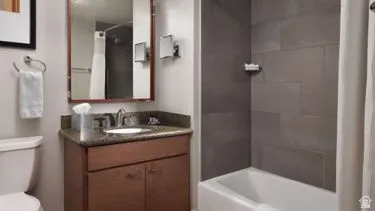 Bathroom featuring a wood-finish vanity with an undermount sink and a speckled countertop