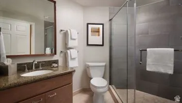 Bathroom featuring a wood-finish vanity with a stone-look countertop, an oval undermount sink, and a framed mirror