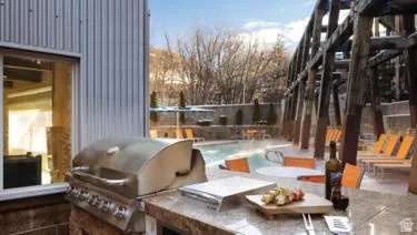 Outdoor kitchen area featuring a built-in stainless steel grill and a stone-finish countertop