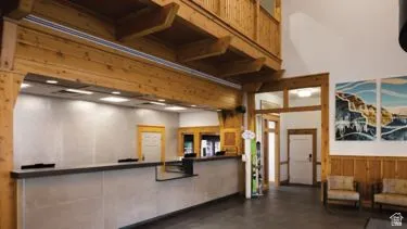 Spacious lobby featuring a prominent reception counter with task lighting, exposed wood beams, and a wood-paneled wall