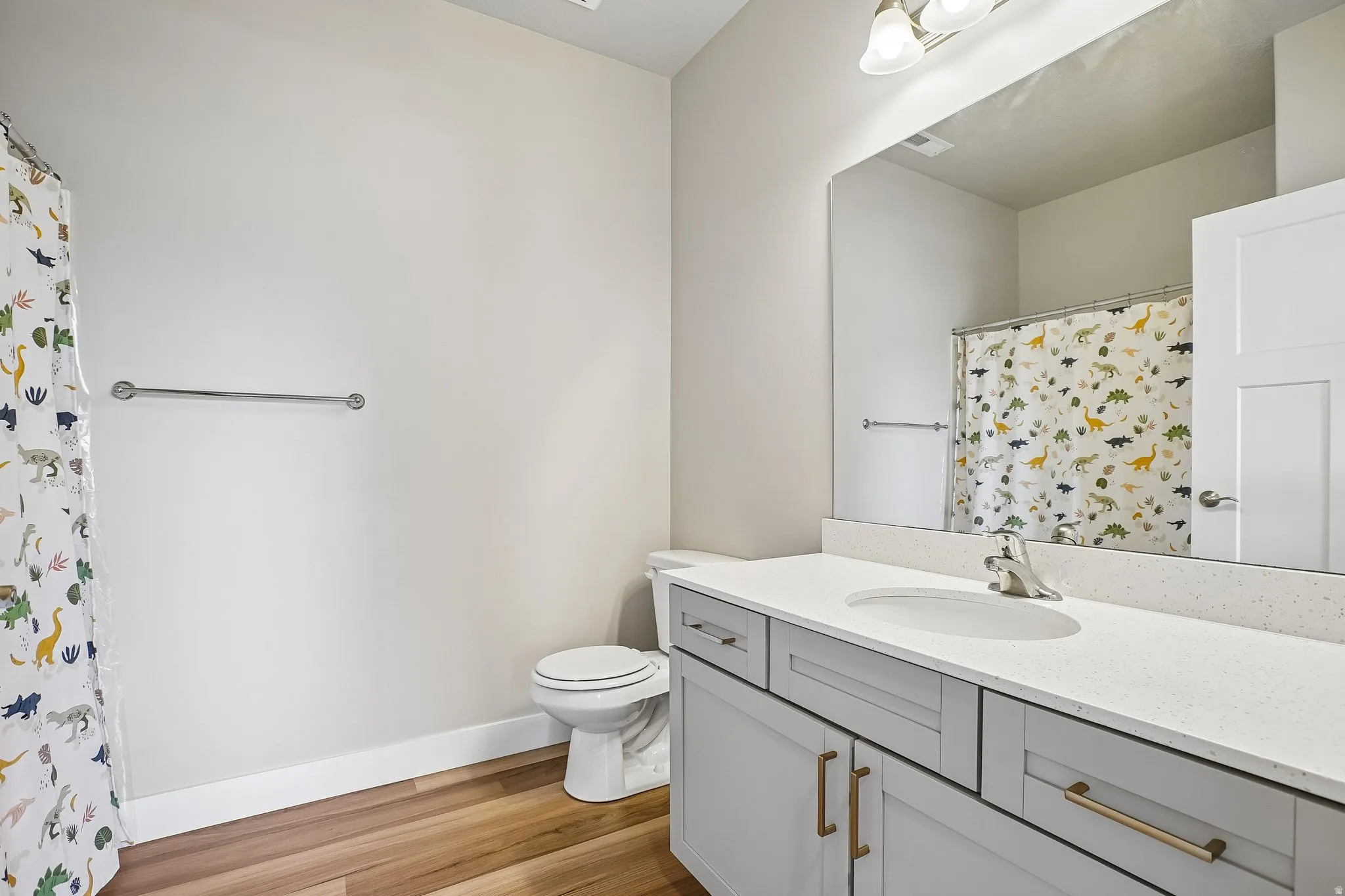 Bathroom featuring a single vanity with light grey cabinetry, a white countertop, and a large wall-mounted mirror