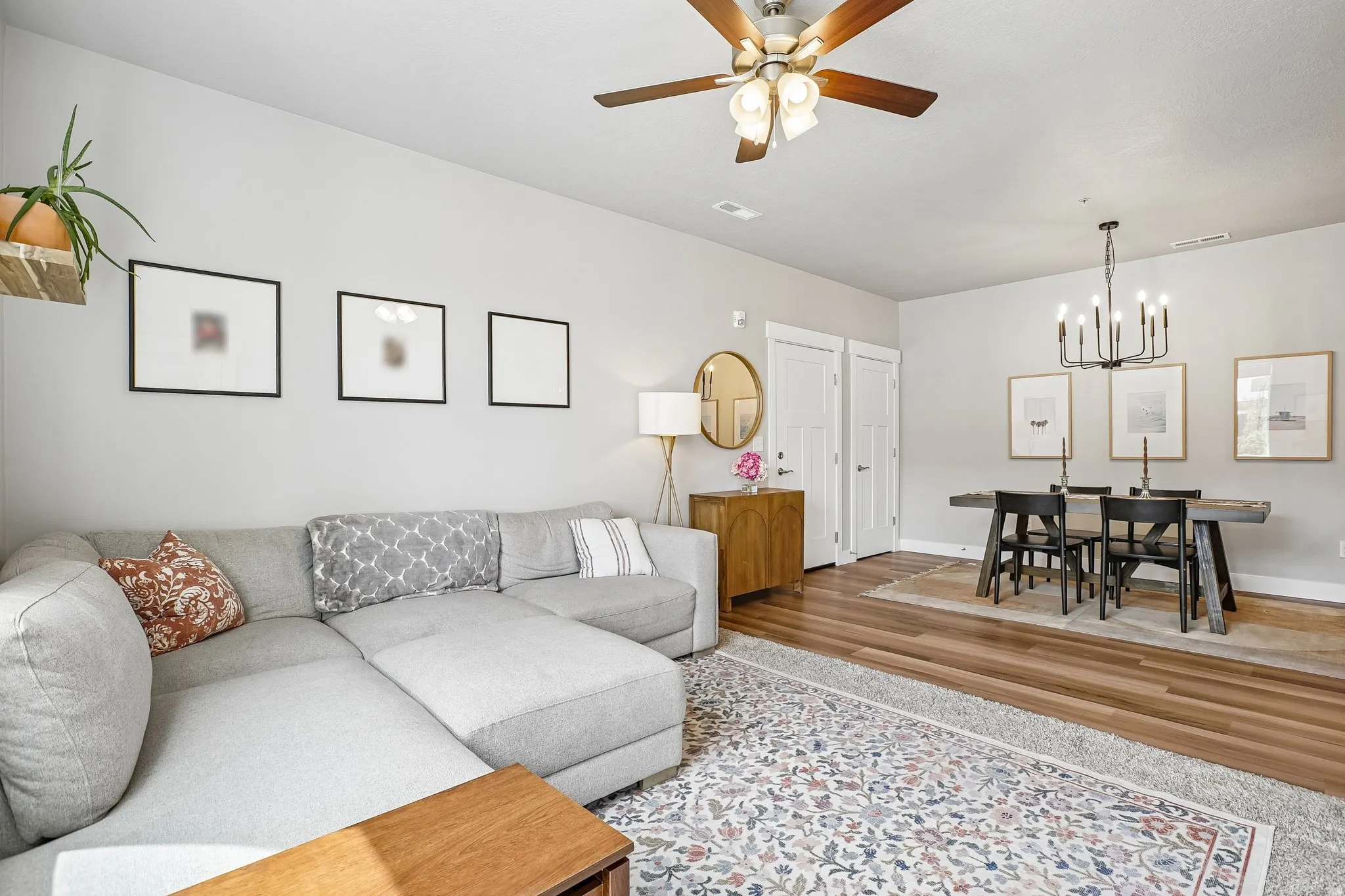 Open-concept living space featuring wood-finish flooring, a contemporary ceiling fan, and a modern black chandelier