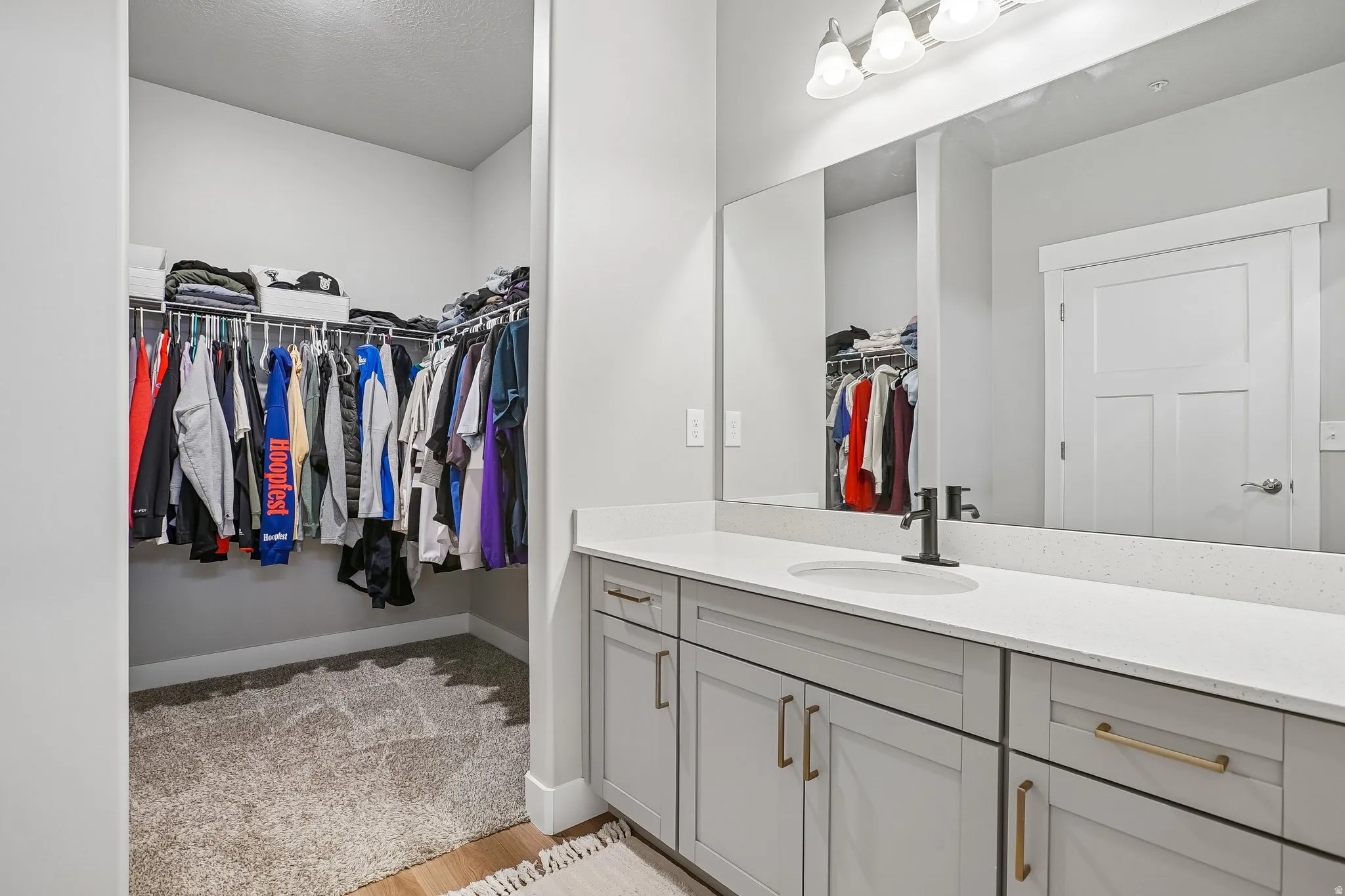 Vanity area featuring a quartz countertop with an undermount sink, matte black faucet, and a large wall-mounted mirror