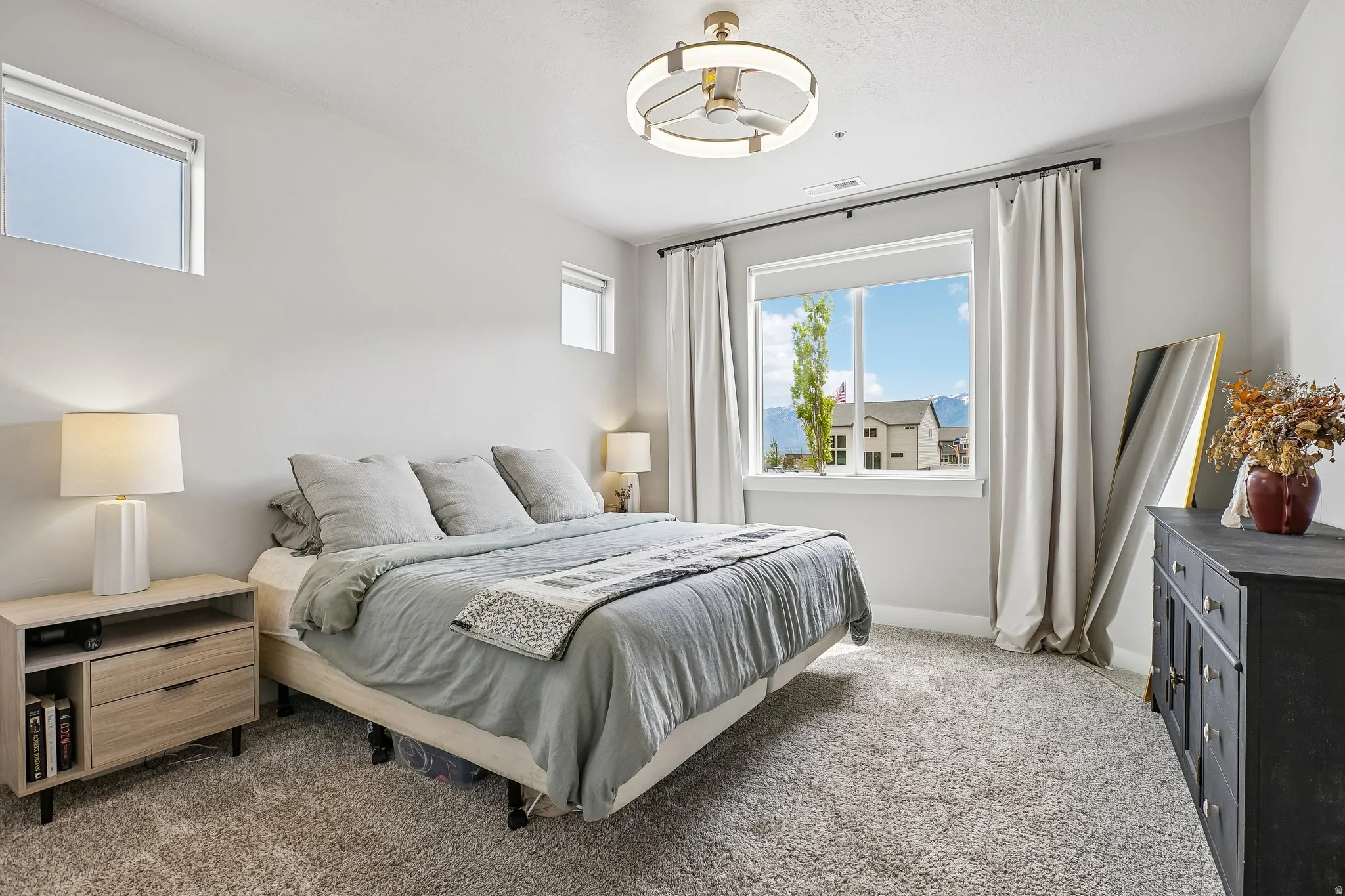 Light-colored carpeting and white walls complement the large window with expansive mountain scenery